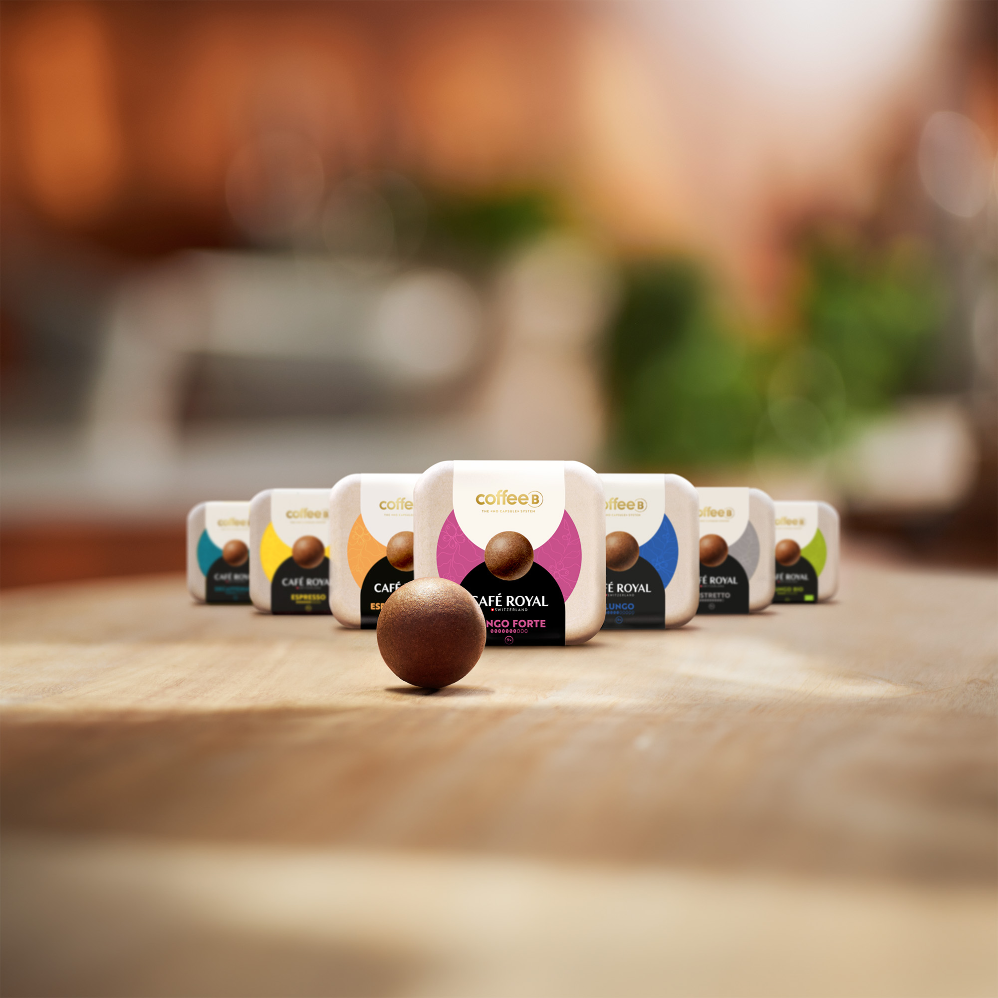 Una sfera di caffè si trova su legno davanti a diverse confezioni colorate.