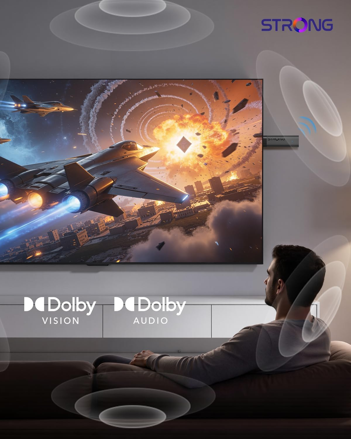 Un hombre se sienta ante un gran televisor que muestra una explosión y aviones, rodeado de logotipos.