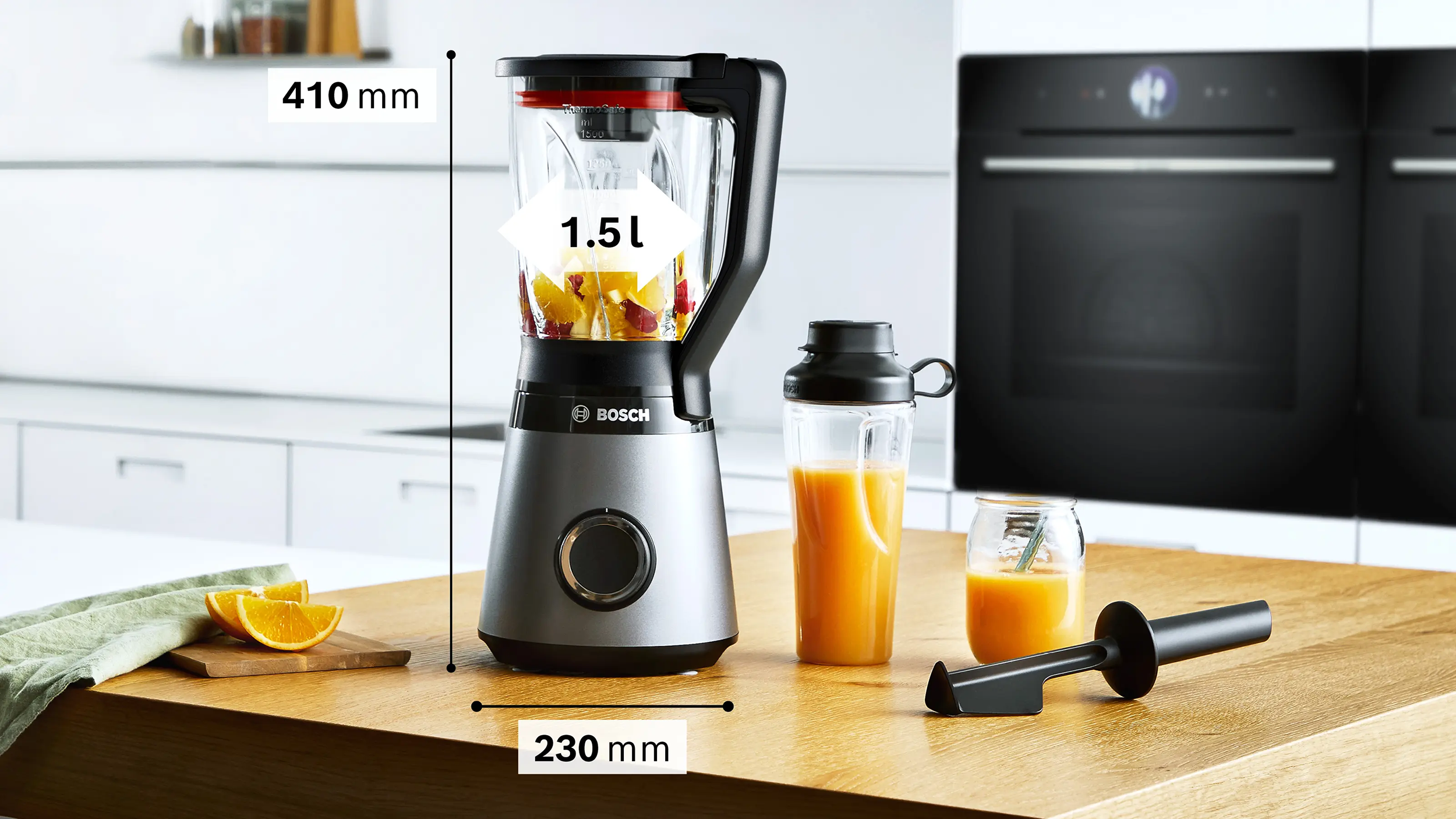 Egy Bosch turmixgép gyümölccsel egy fa pulton, mellette smoothie és narancsszeletek.