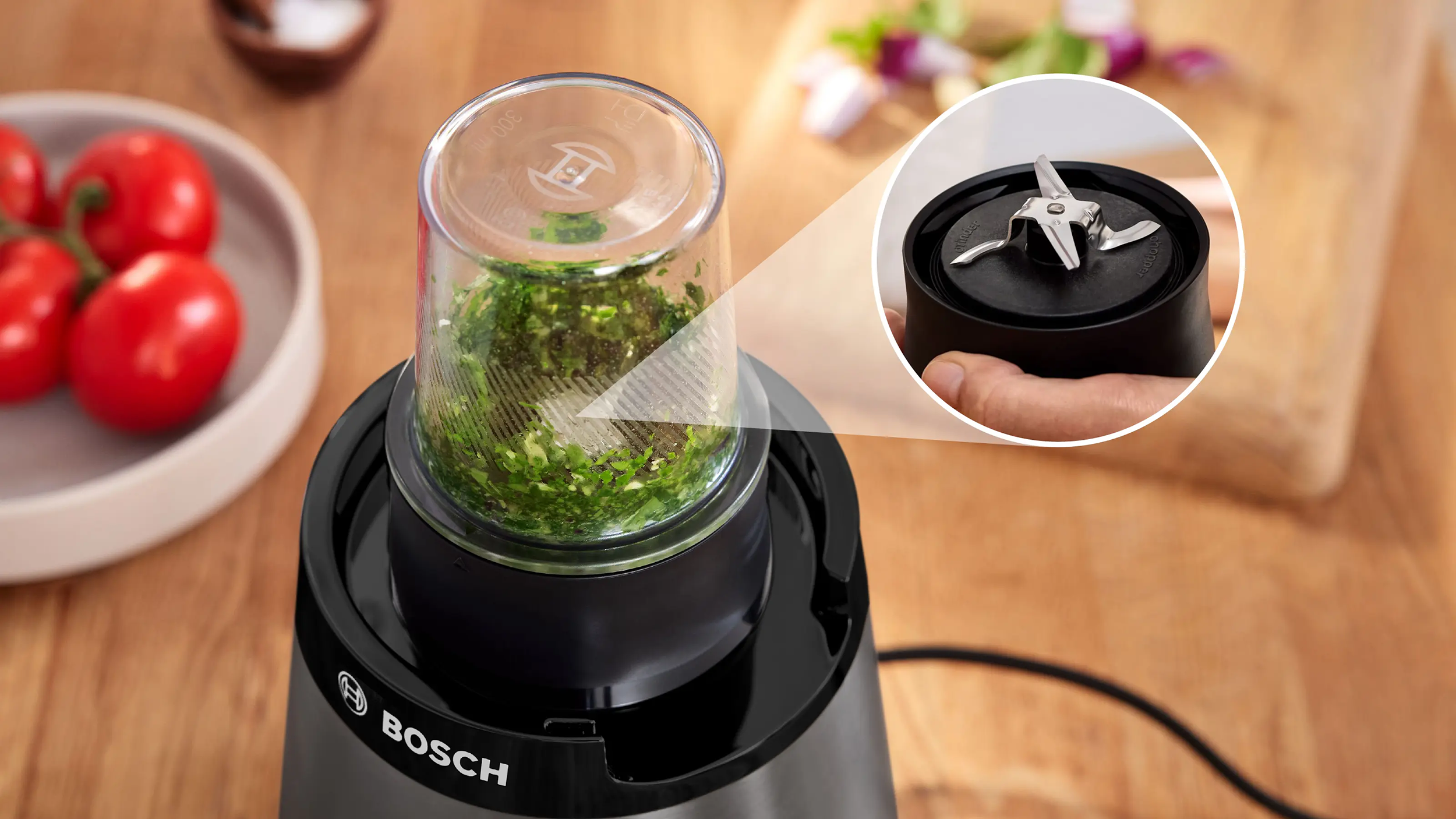Bosch aprító zöldfűszerekkel az üvegedényben és a négyágú rozsdamentes acél penge részlete.