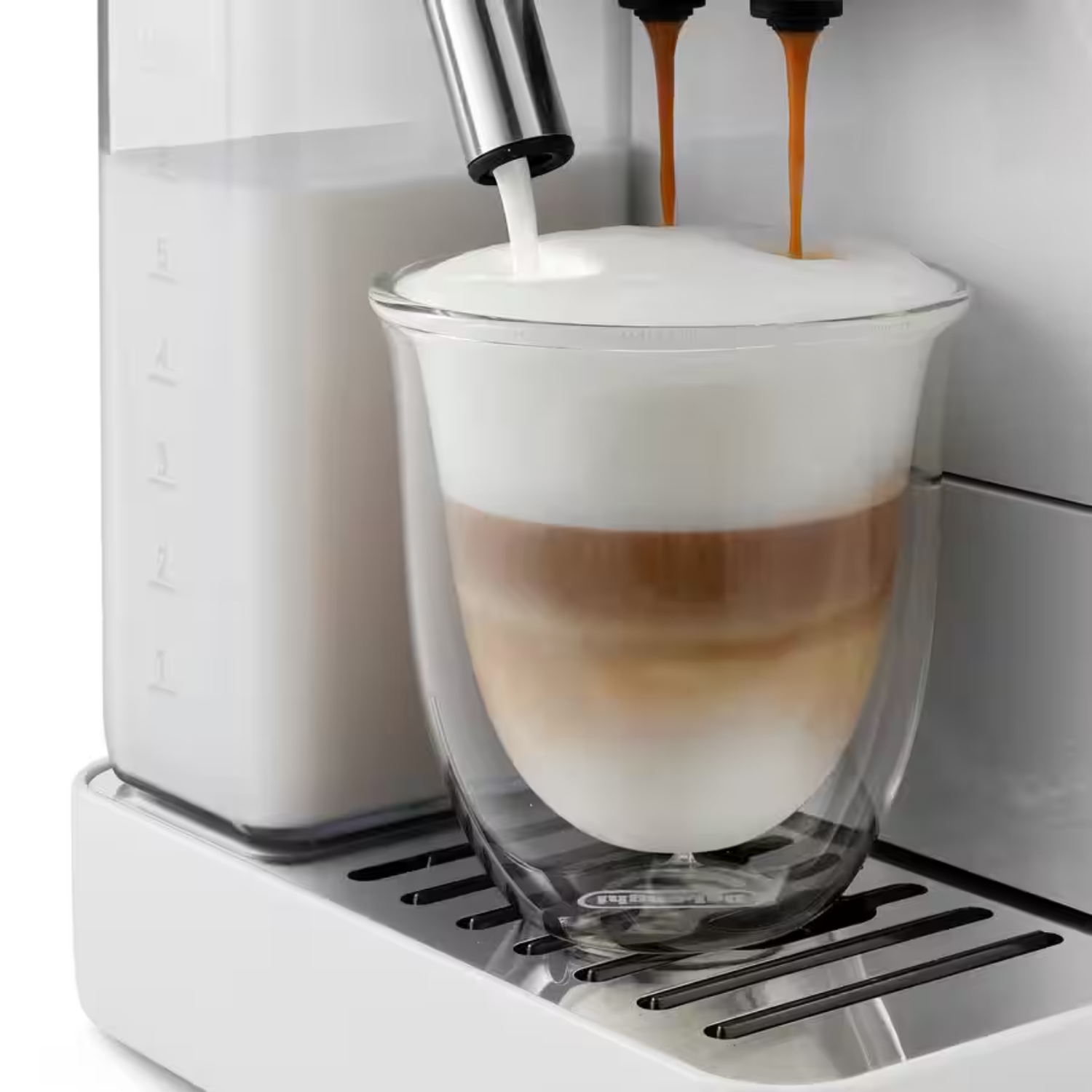 Una cafetera vierte leche y café en un vaso, formando capas.
