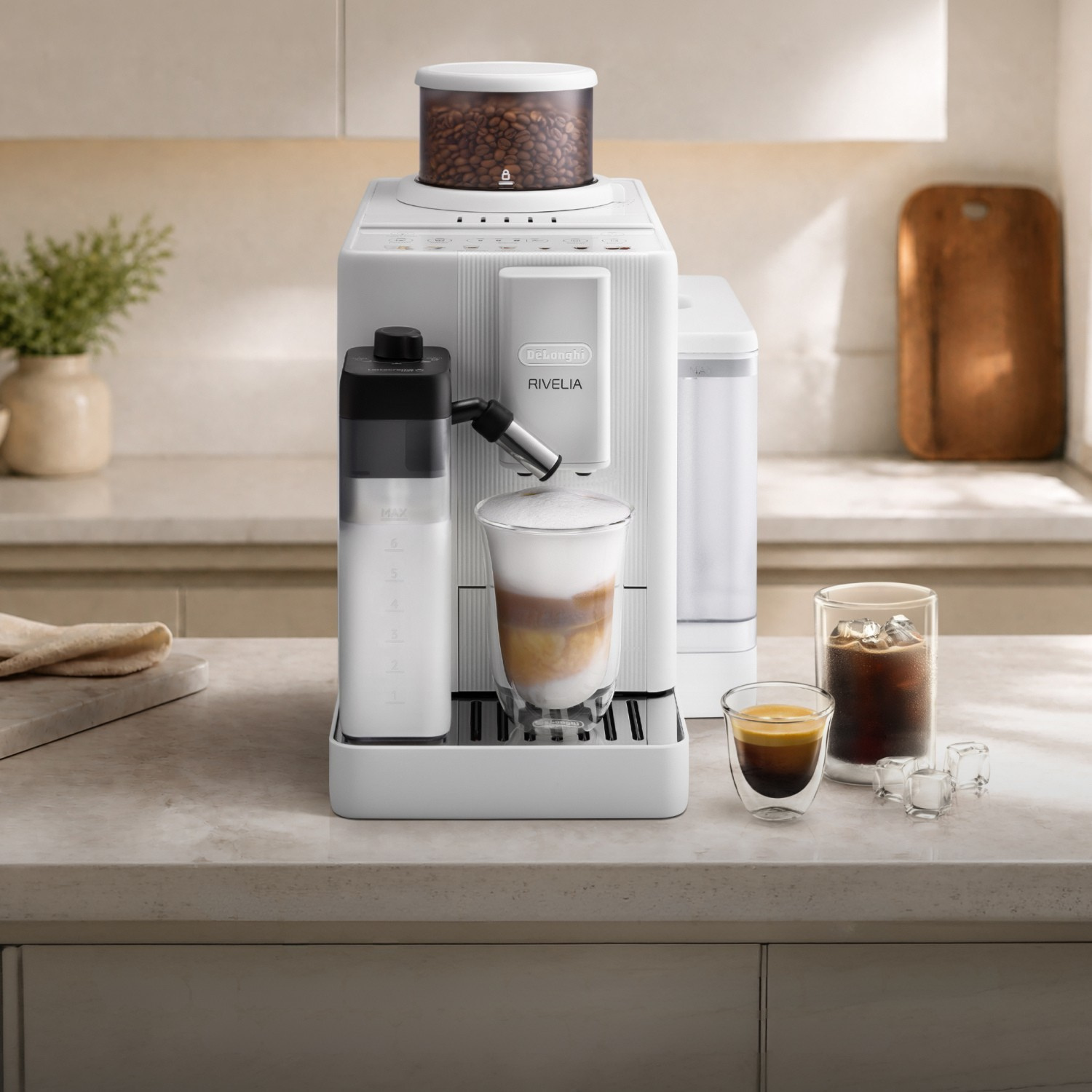 Una cafetera blanca De'Longhi Rivelia en una encimera de cocina con bebidas de café.
