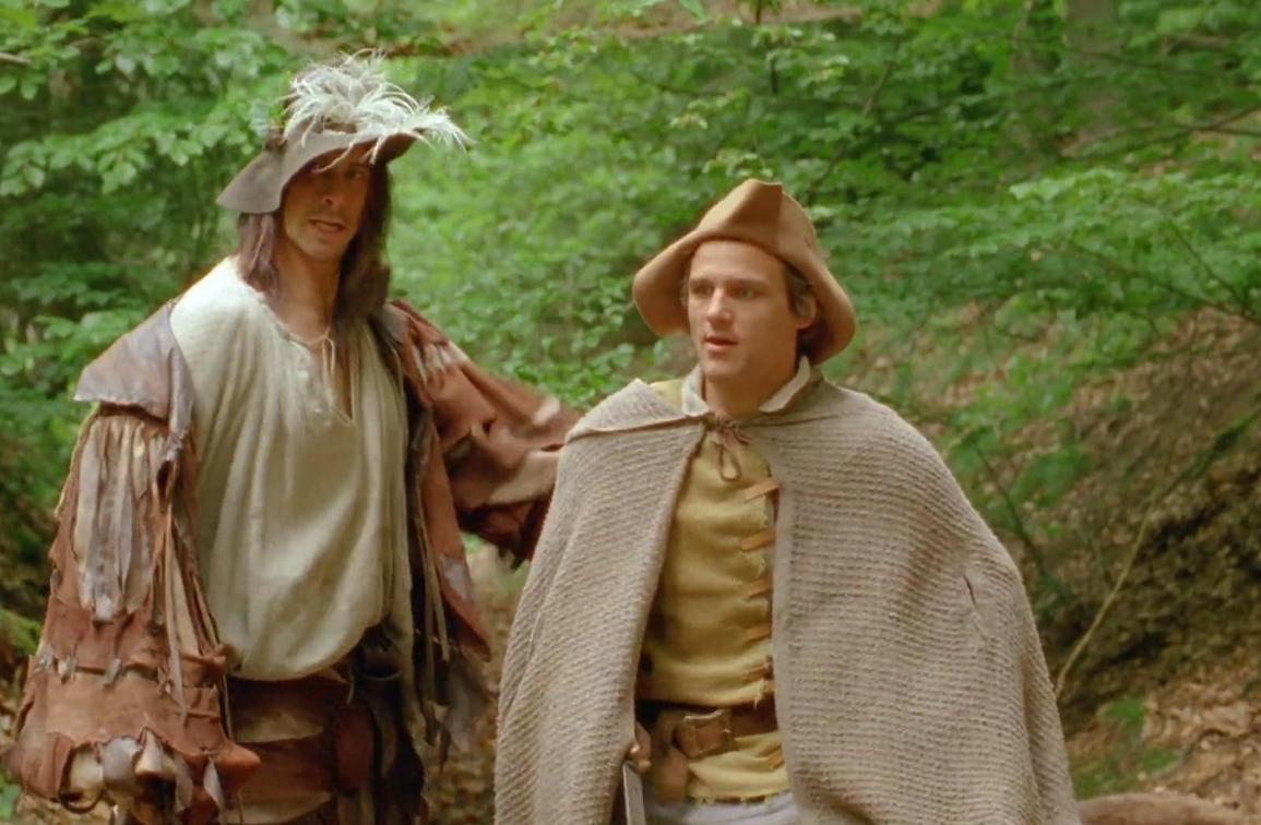 Zwei Männer in historischen Gewändern und Hüten stehen im Wald.
