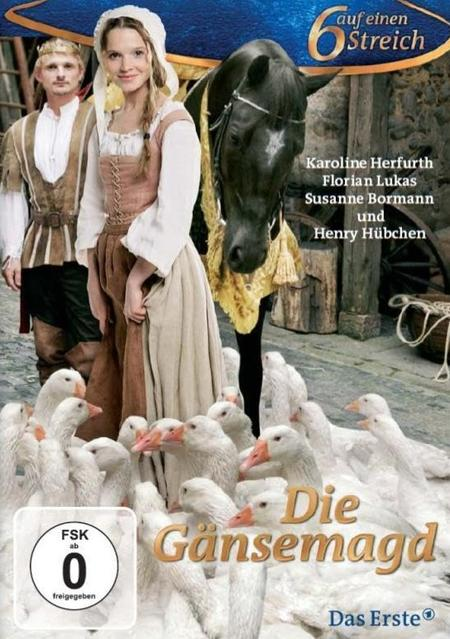Ein Mann und eine Frau in mittelalterlicher Kleidung stehen neben einem schwarzen Pferd, umgeben von Gänsen.