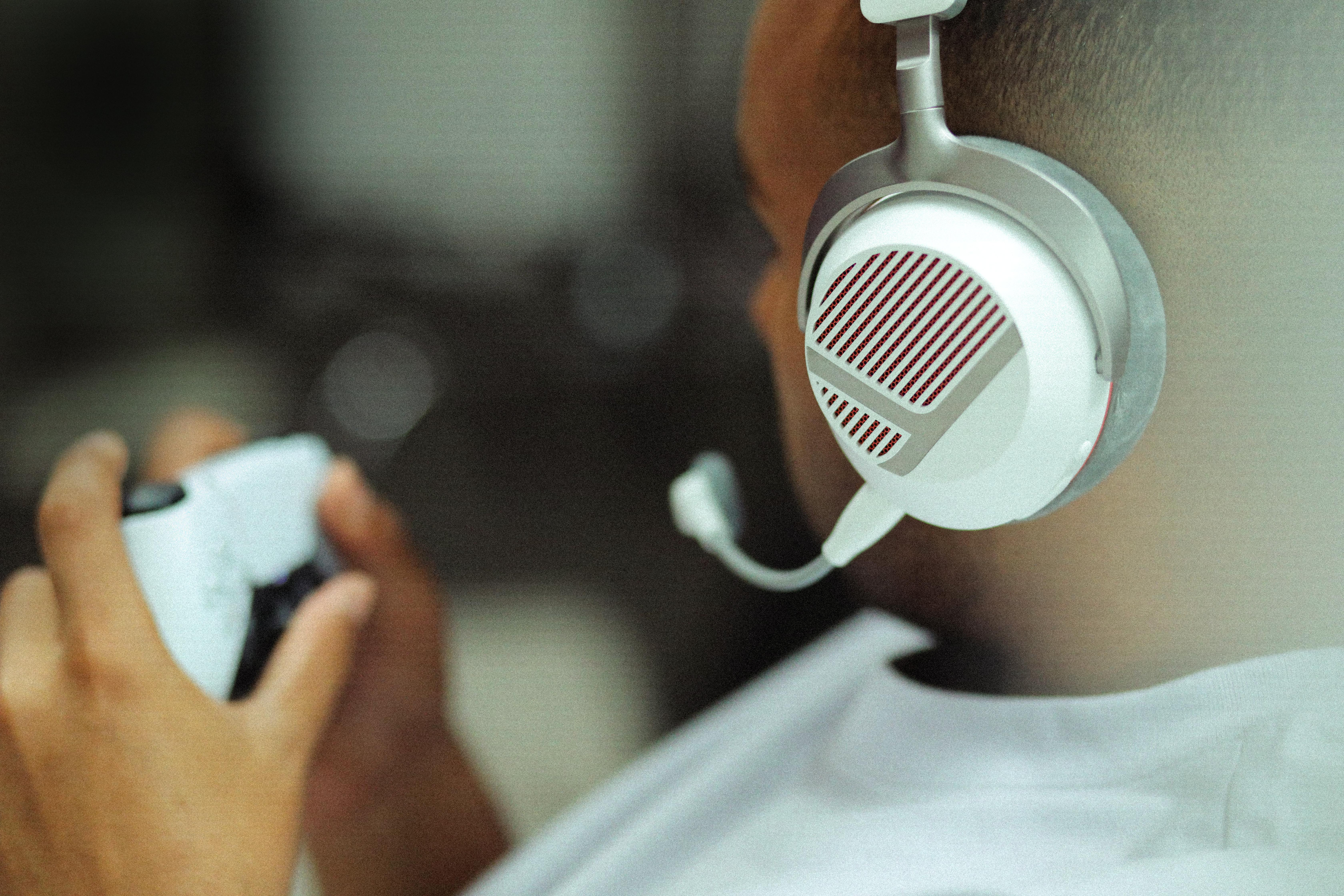 Ein Gamer mit weißem Headset und Mikrofon hält einen Controller in der Hand.