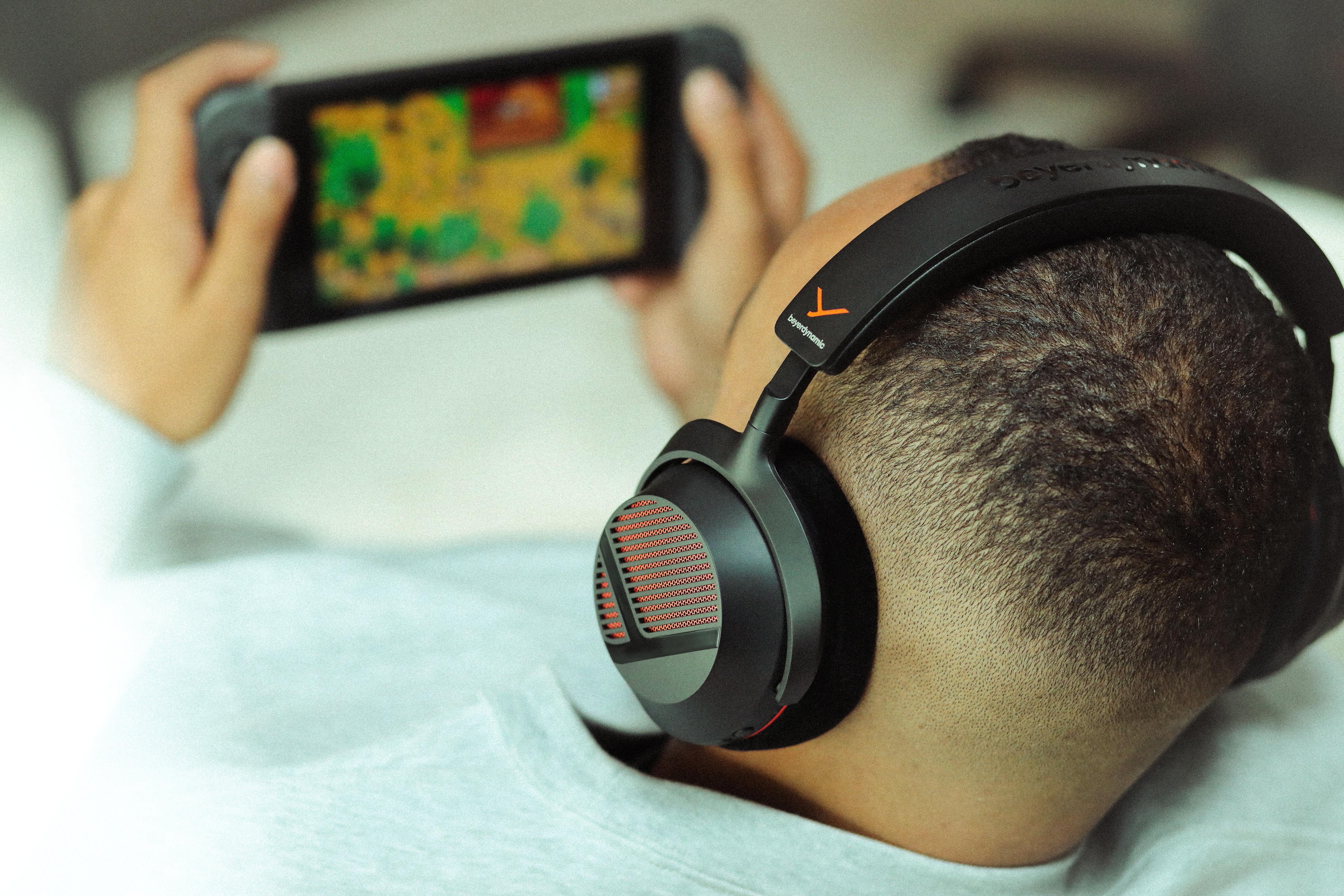 Ein Mann mit schwarzen Kopfhörern spielt Handheld-Videospiele.