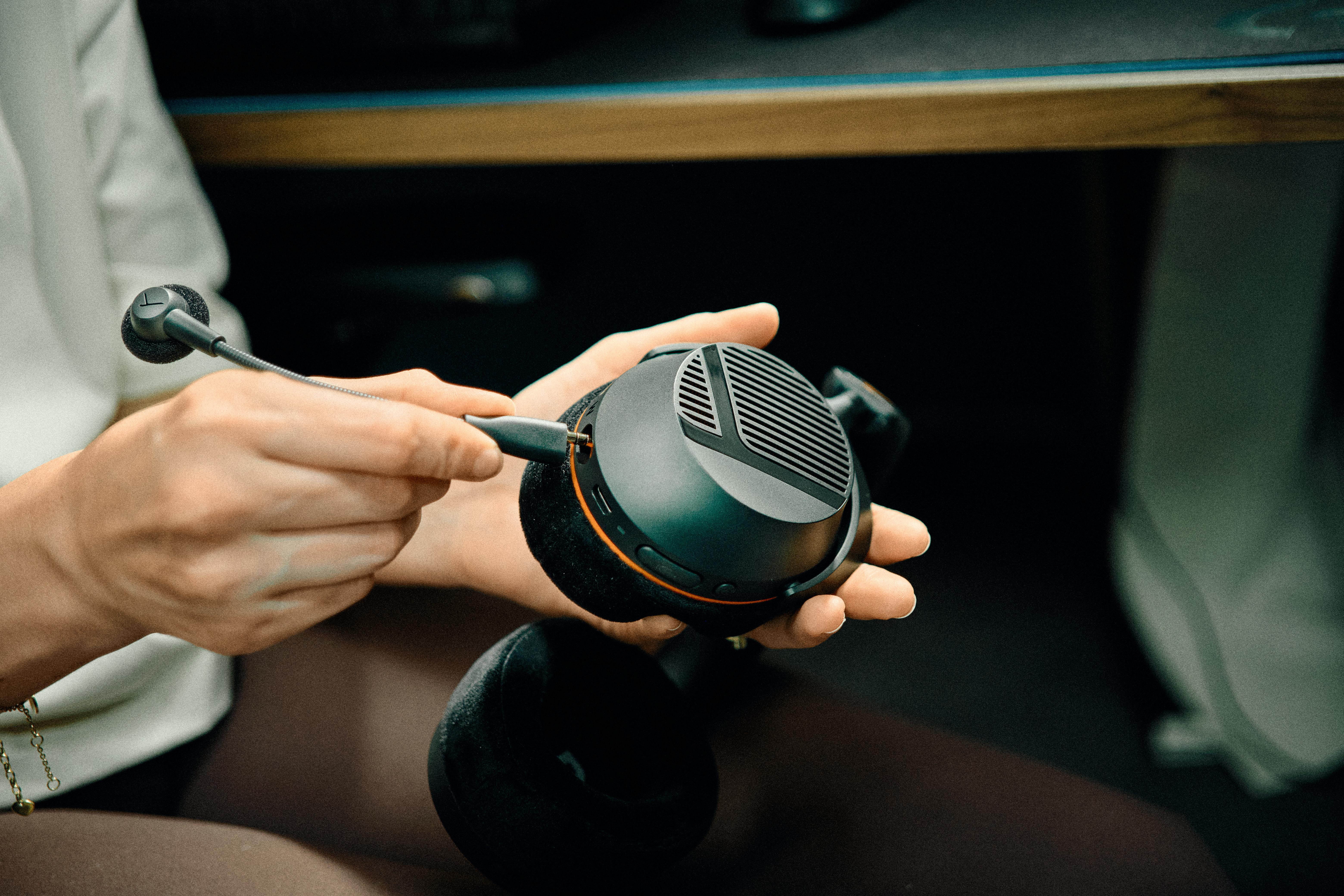 Eine Person steckt ein abnehmbares Mikrofon in ein schwarzes Gaming-Headset in ihren Händen.
