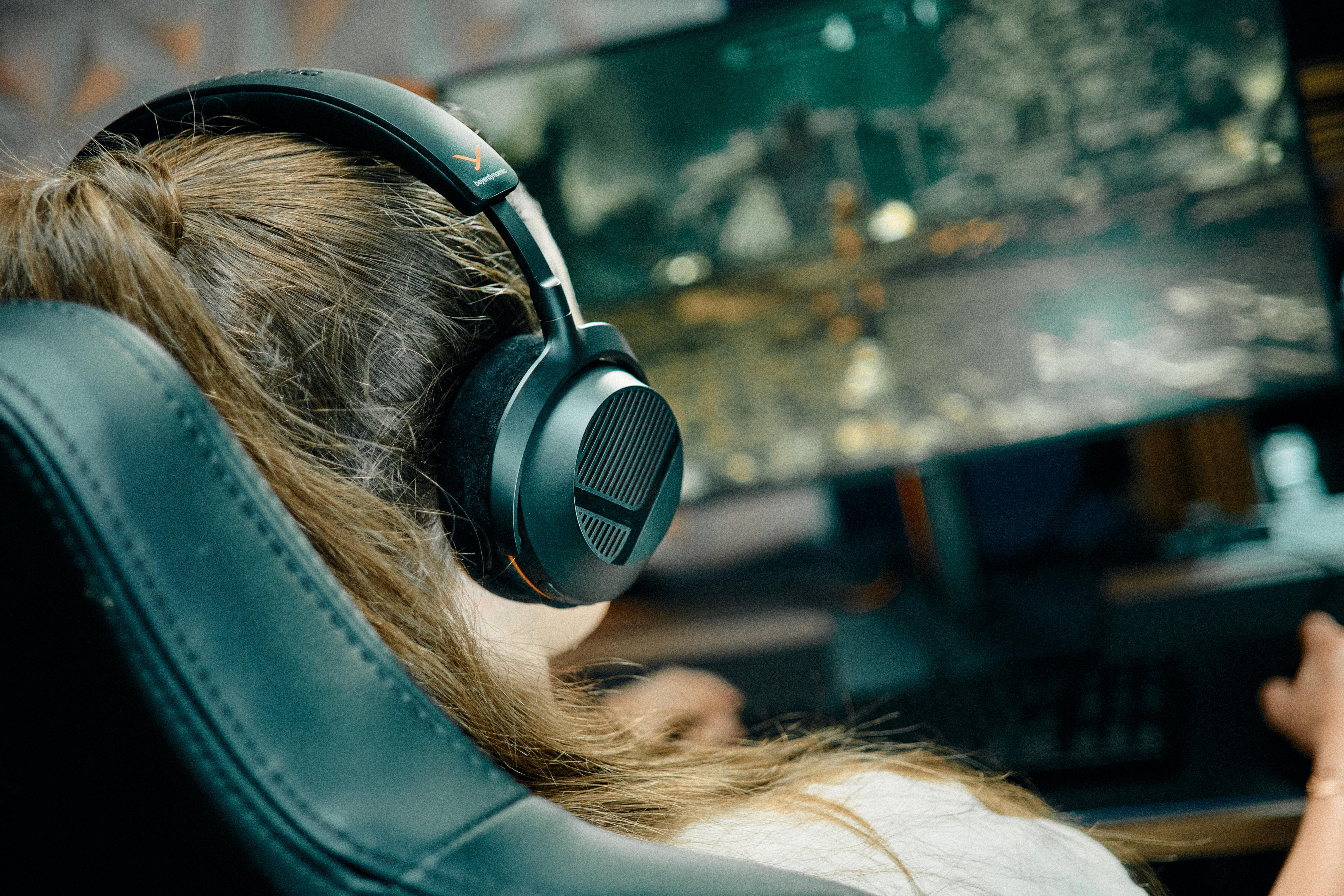 Eine Spielerin mit Kopfhörern sitzt vor einem beleuchteten Computermonitor.