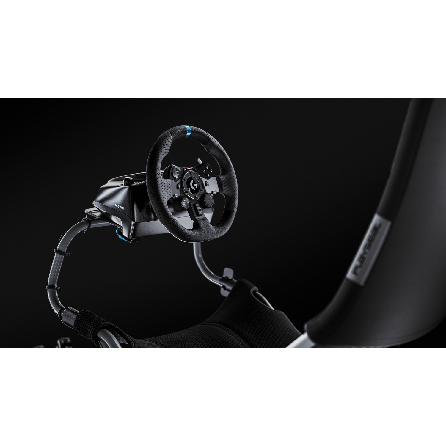 A black racing wheel with buttons and a blue marker is mounted on a metal frame, in front of a black seat.