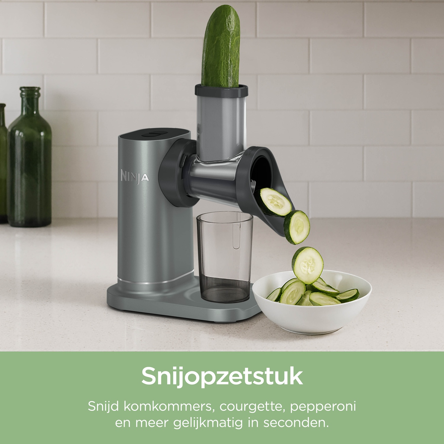 Gray Ninja grater slicing a cucumber into pieces falling into a bowl.