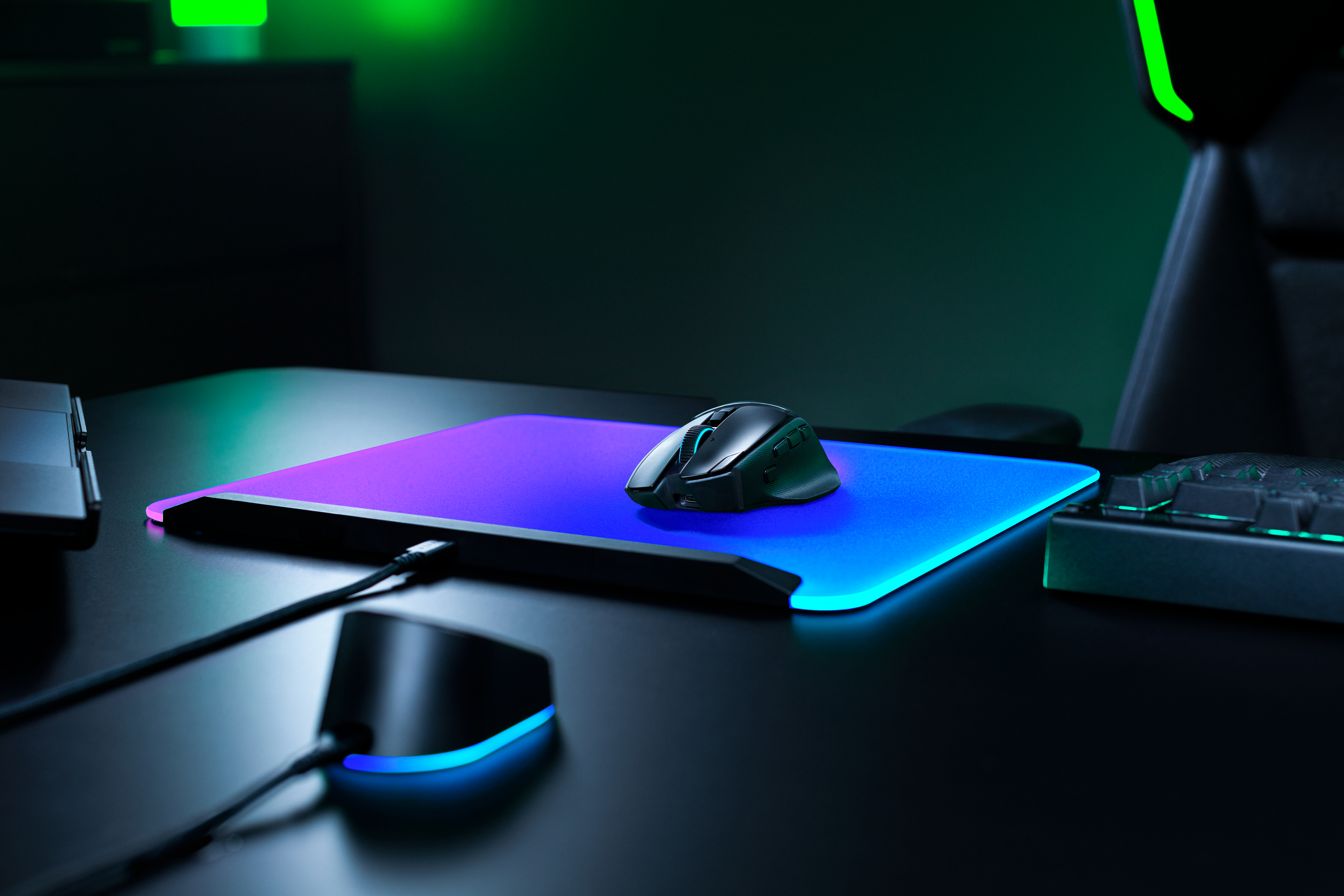 Eine schwarze Gaming-Maus auf einem leuchtend blauen und violetten Mauspad auf einem dunklen Schreibtisch.