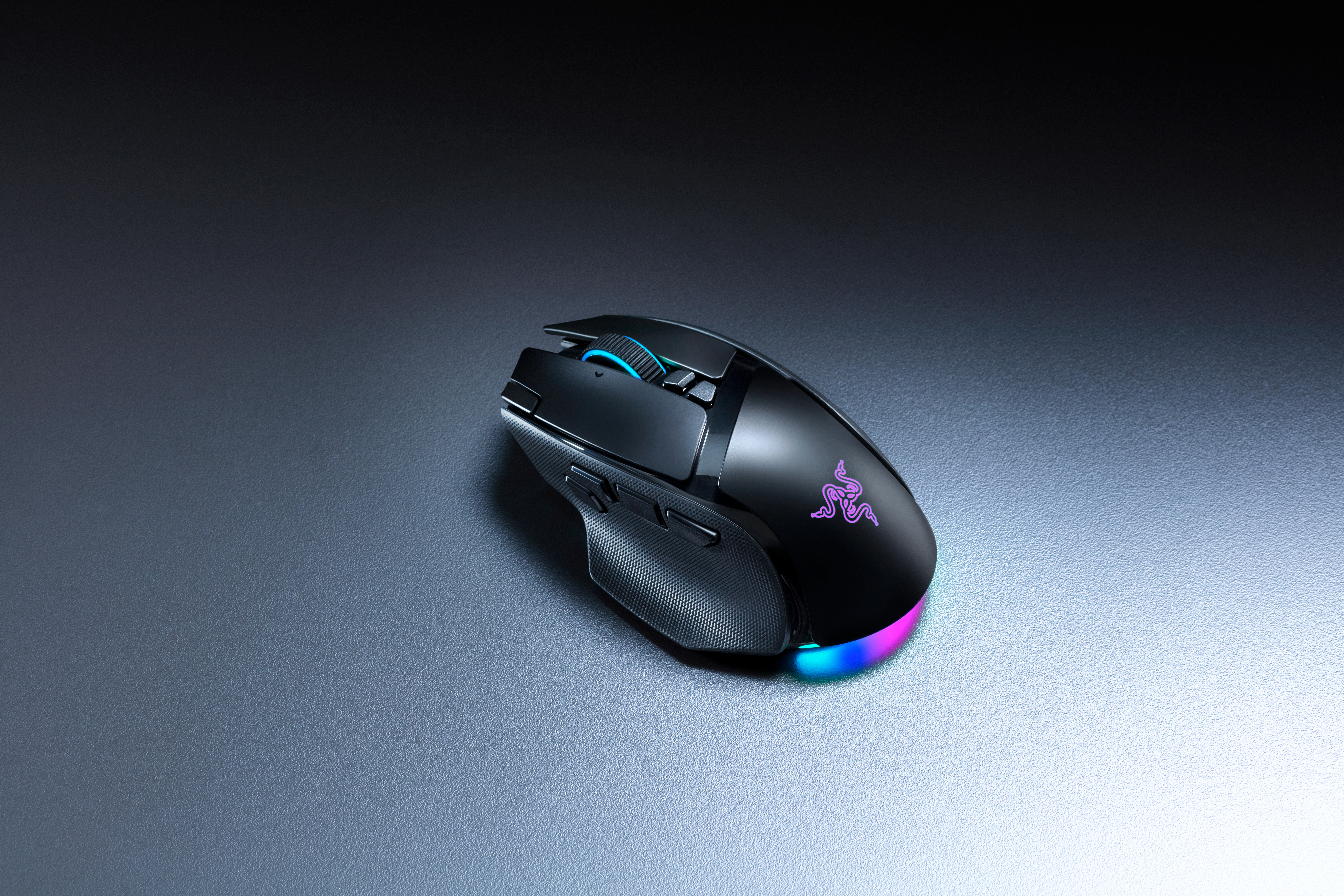 Schwarze Gaming-Maus mit RGB-Beleuchtung auf einer grauen Unterlage.