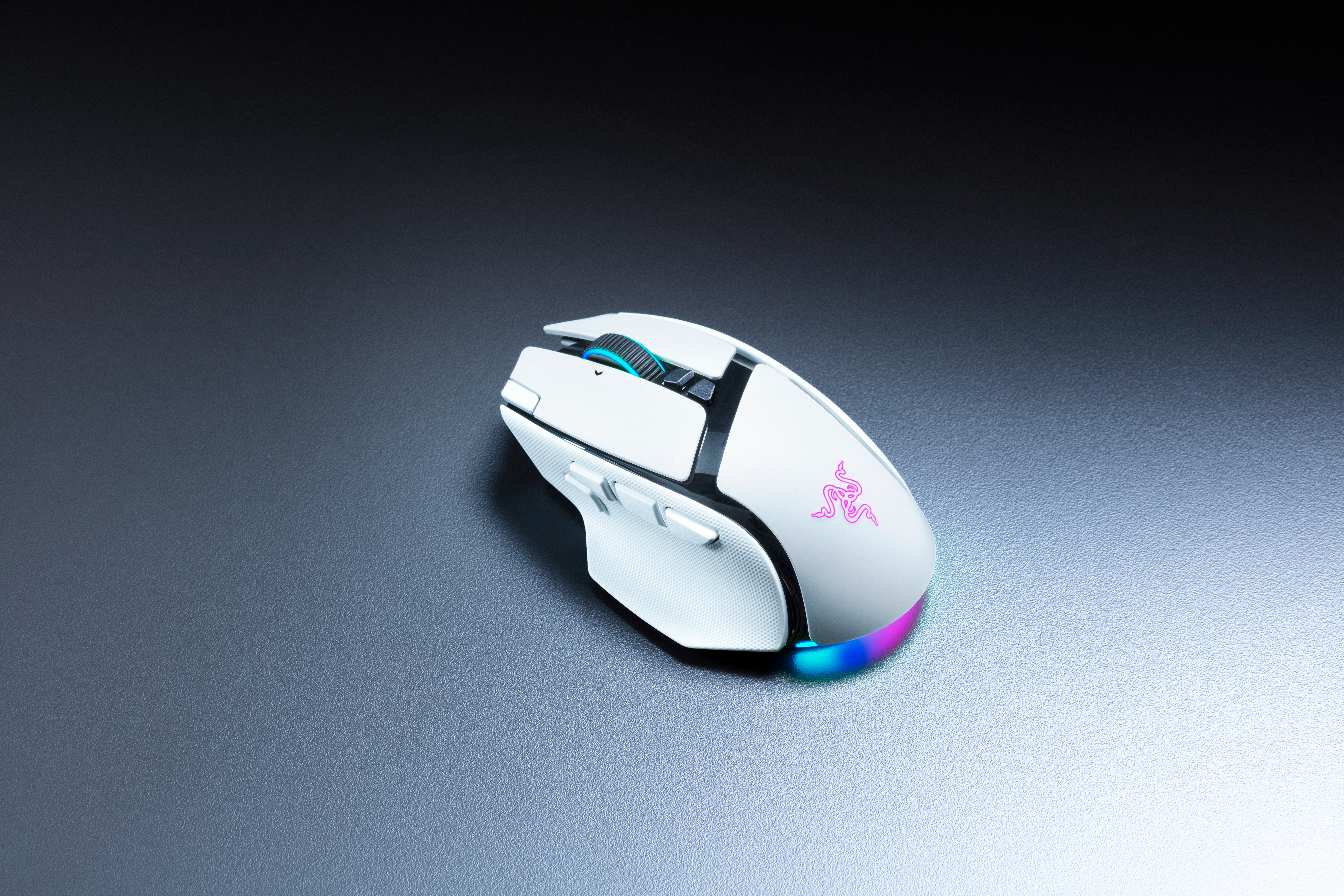Eine weiße Gaming-Maus mit RGB-Beleuchtung liegt auf einer grauen Oberfläche.