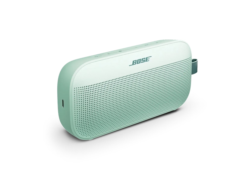 Ein mintgrüner tragbarer Bose-Lautsprecher mit einem Stoffgriff steht isoliert vor einem schwarzen Hintergrund.