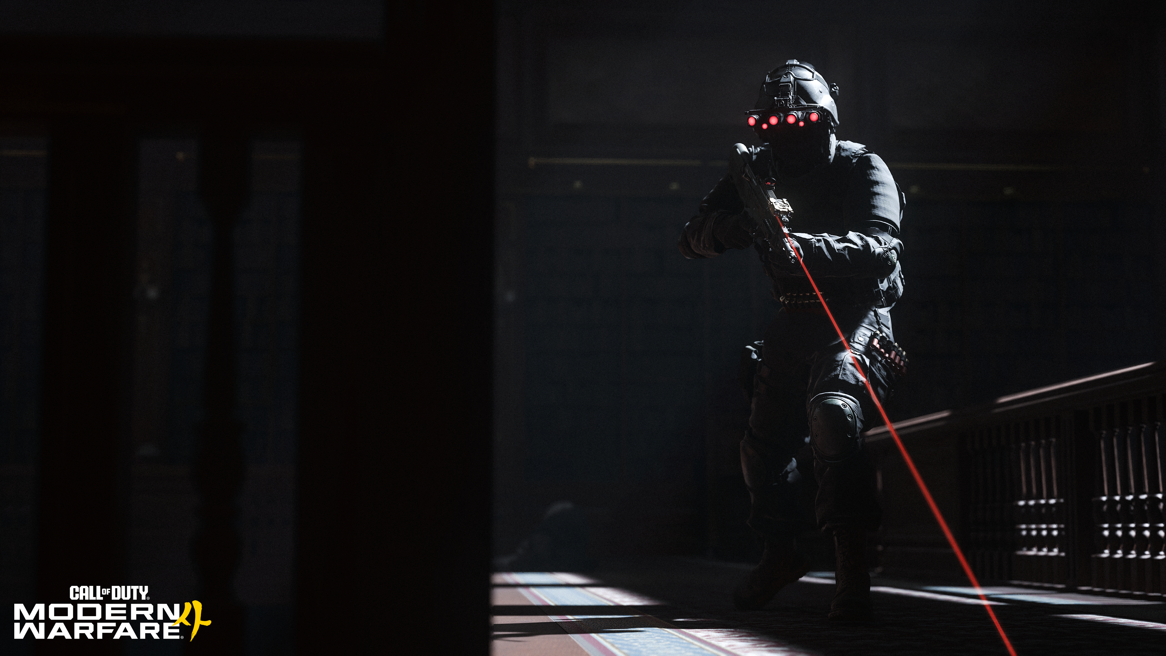 Ein Soldat in dunkler Kampfausrüstung mit Nachtsichtgeräten hält ein Gewehr mit rotem Laser in einem Gebäude.