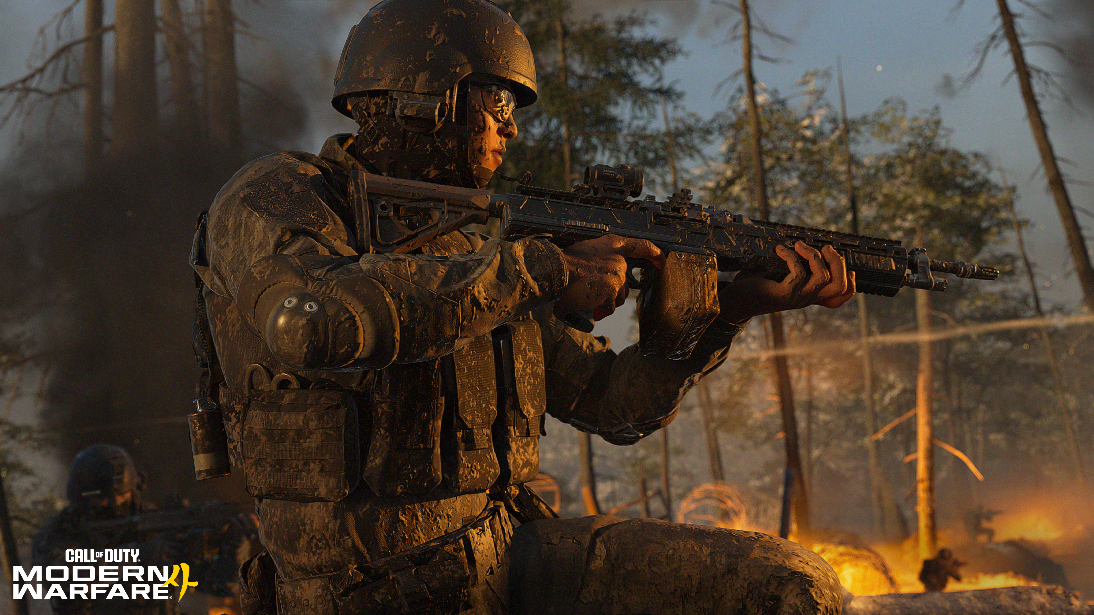 Ein Soldat im Tarnanzug und Helm kniet in einem brennenden Wald und hält ein Sturmgewehr.