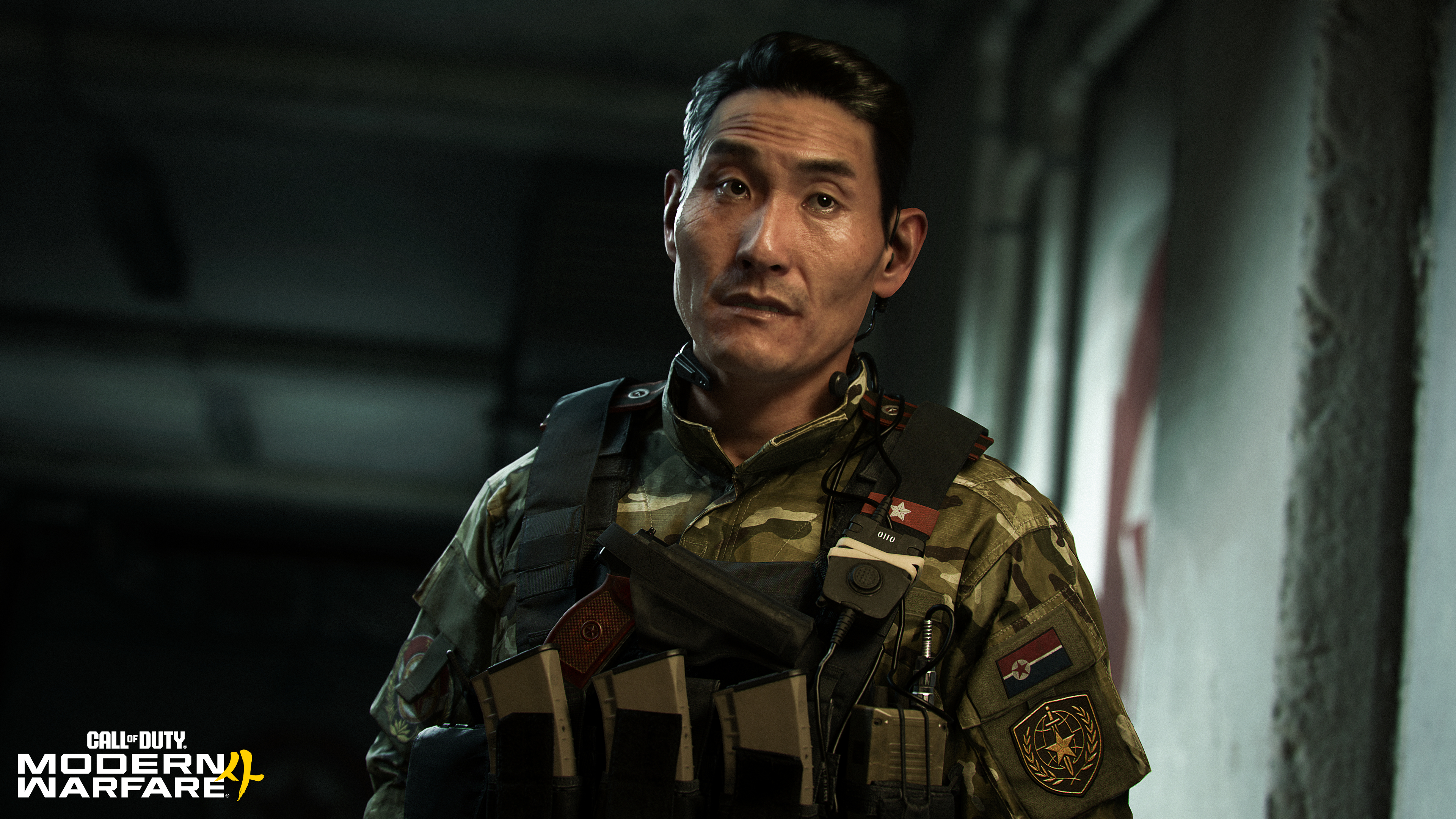 Ein asiatischer Soldat in Tarnkleidung und taktischer Weste schaut ernst in die Kamera.