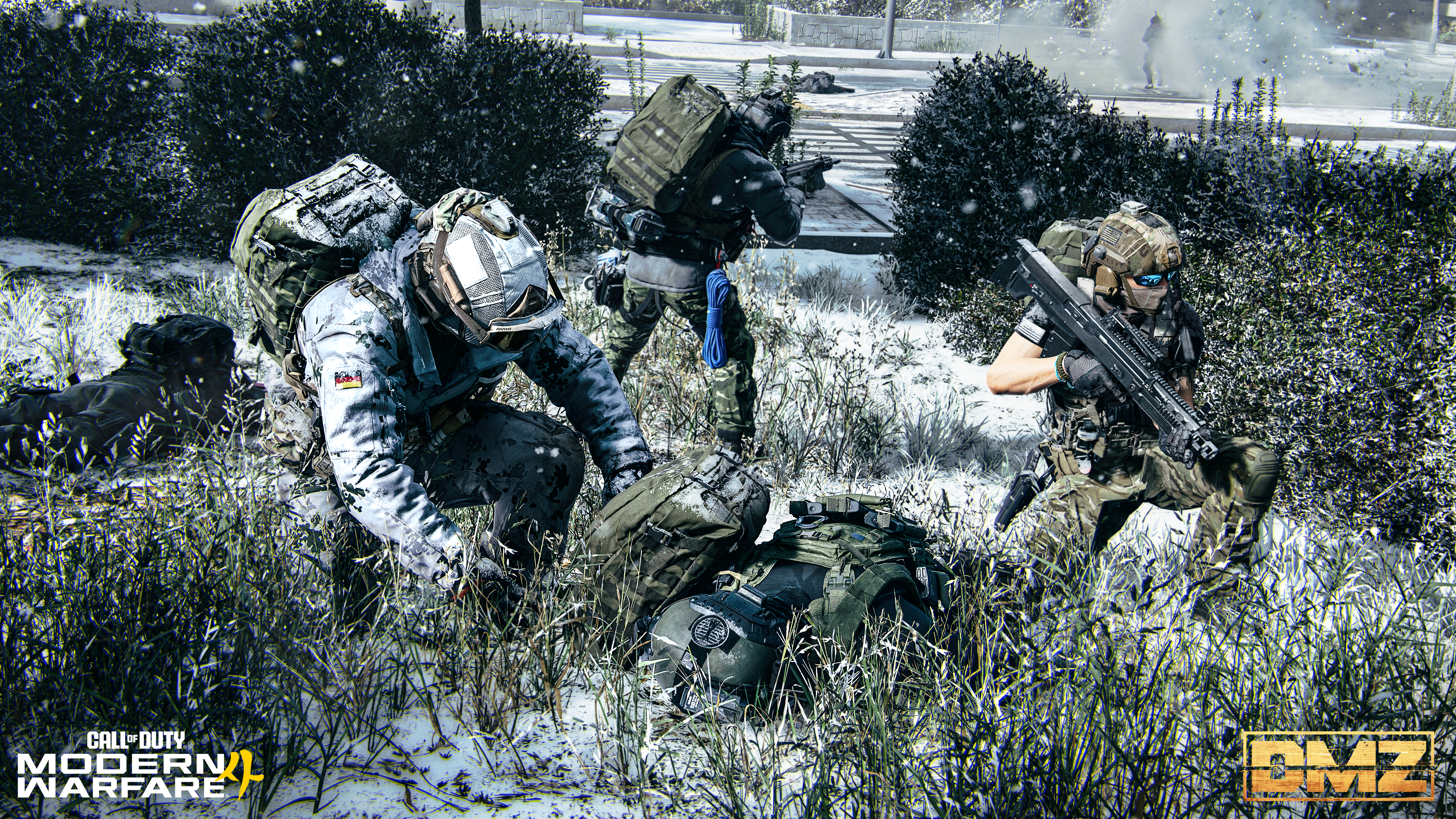 Drei Soldaten in Winterausrüstung kauern in verschneitem Gras neben Rucksäcken und Büschen.