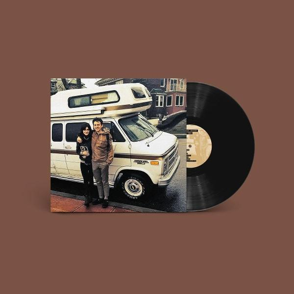 Ein Vinyl-Schallplatten-Cover zeigt ein Paar stehend vor einem weißen Wohnmobil auf einer straße.