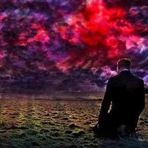 Ein Mann im Anzug steht im offenen Feld unter einem dramatischen, rot und lila gefärbten Himmel.