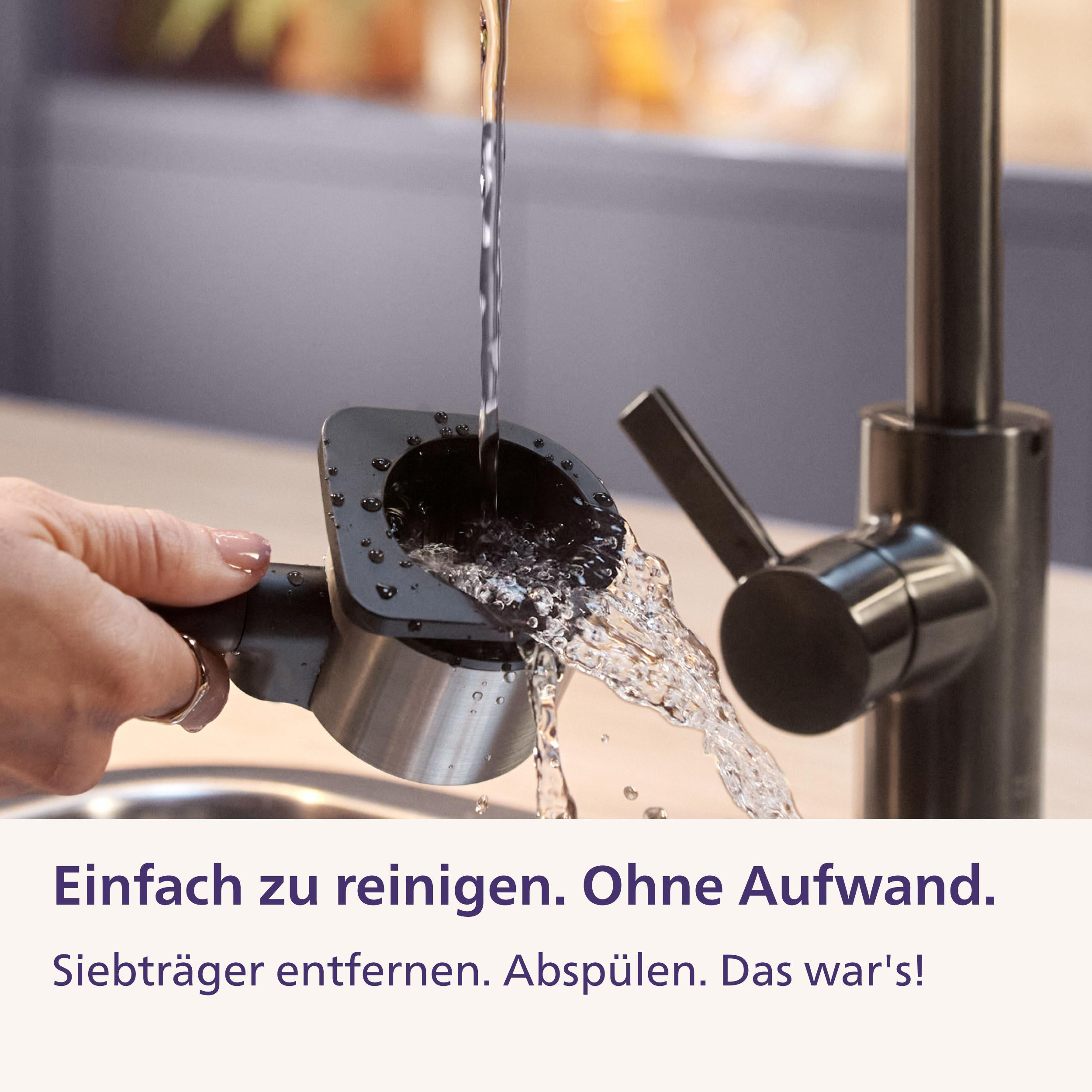 Wasser läuft aus einem Küchenhahn in einen von einer Hand gehaltenen Edelstahl-Siebträger.