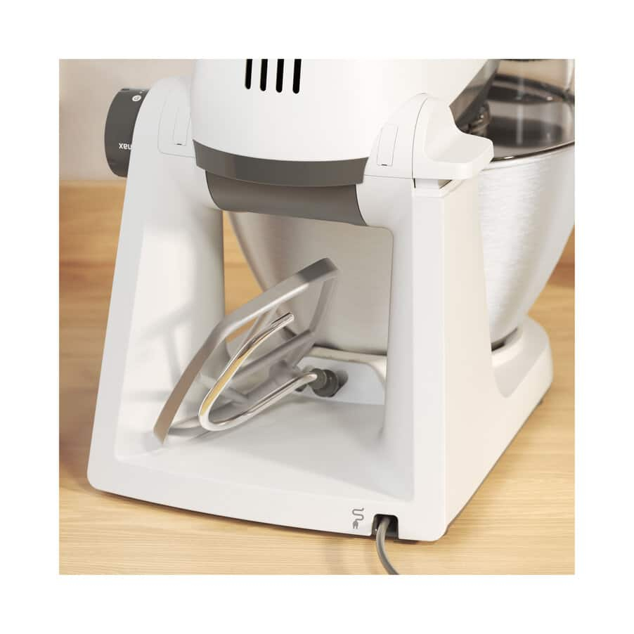Primer plano de una batidora de cocina blanca con un accesorio mezclador de acero inoxidable.