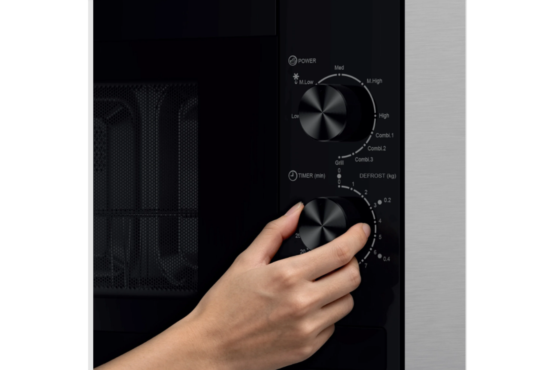 Una mano gira la perilla del temporizador en el panel de control negro de un microondas.