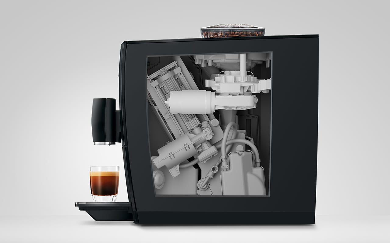 Widok z boku ekspresu do kawy ukazujący jego wewnętrzne mechanizmy i filiżankę espresso.