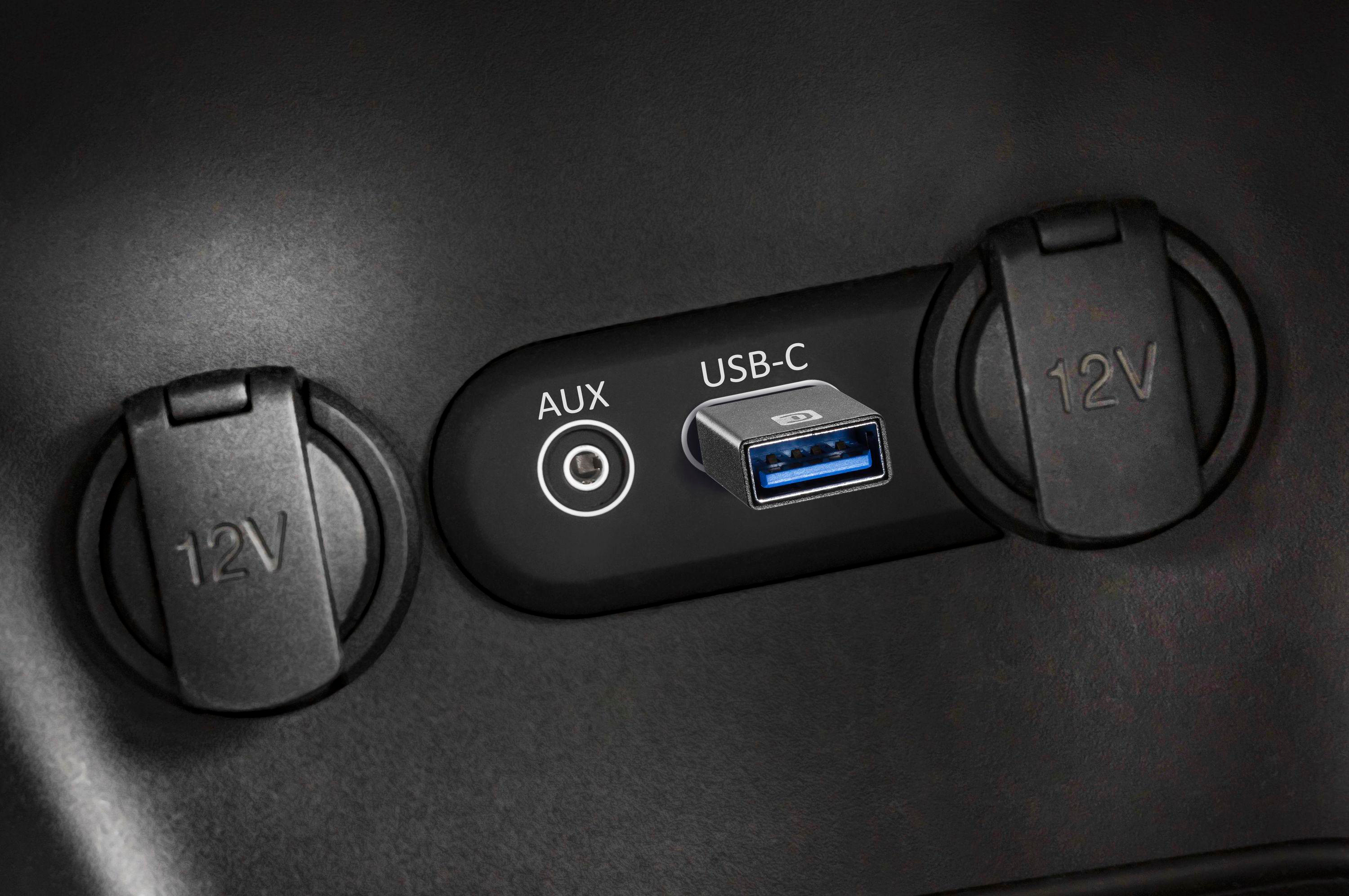 Ein Auto-Armaturenbrett mit zwei 12V-Steckdosen, einem AUX-Anschluss und einem USB-C-Anschluss mit Adapter.
