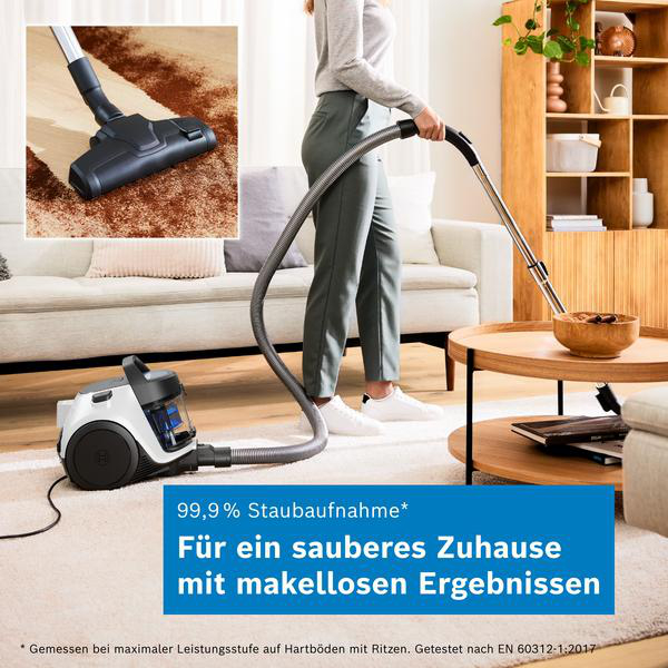 Eine Frau saugt Teppich in einem modernen Wohnzimmer mit einem weißen Staubsauger.