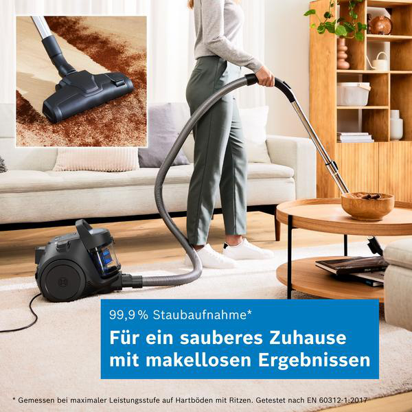 Eine Person saugt einen Teppich in einem hellen Wohnzimmer mit einem schwarzen Staubsauger und blauem Text.