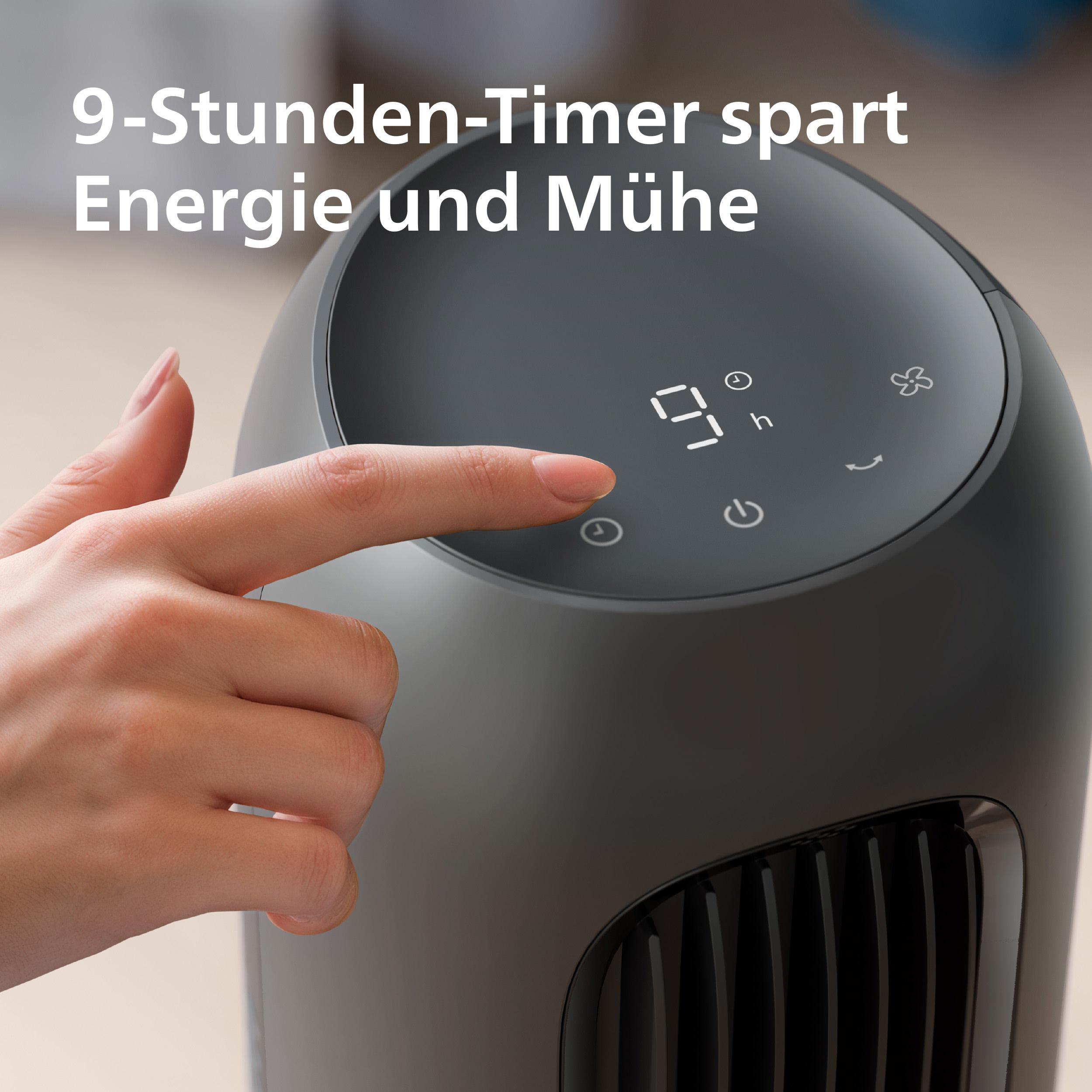 Eine Hand tippt auf das Display eines grauen Säulenheizgeräts mit 9-Stunden-Timer.