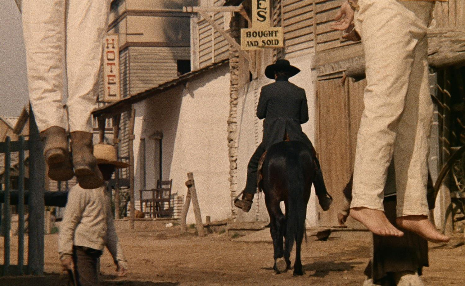 Ein Reiter in einem Western-Dorf, im Vordergrund hängen Beine von Hingerichteten.