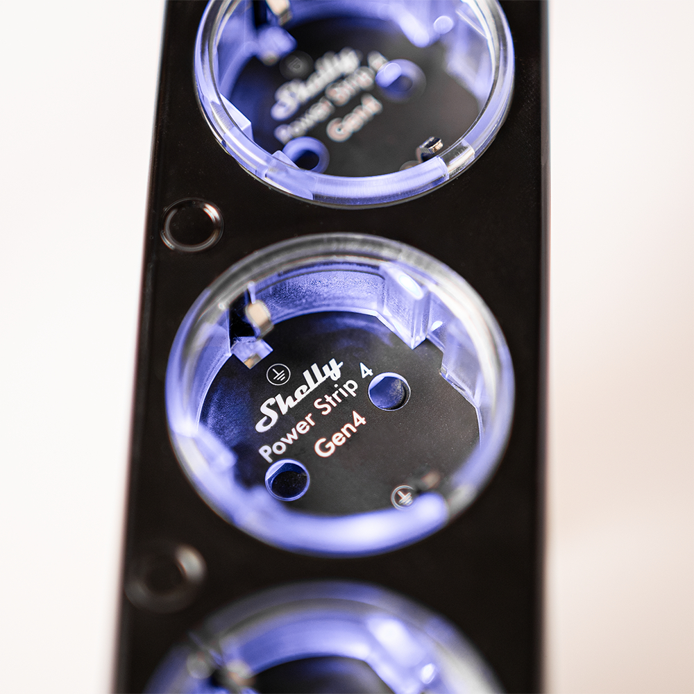 Schwarze Shelly Power Strip 4 Gen4 Mehrfachsteckdose mit blauem Leuchtring auf weißem Hintergrund.