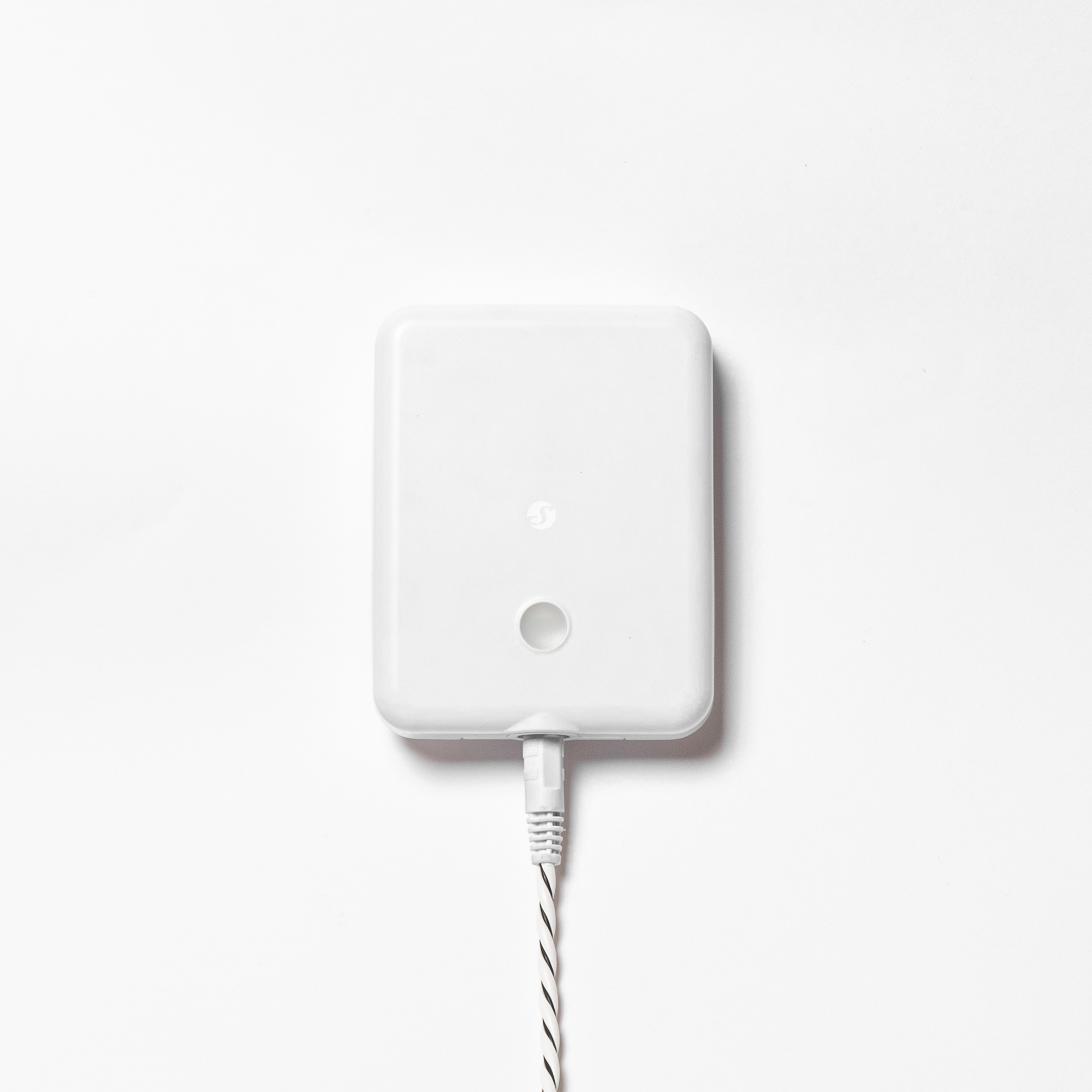 Ein weißes, rechteckiges Gerät mit einem Kabel ist zentral vor einem weißen Hintergrund platziert.