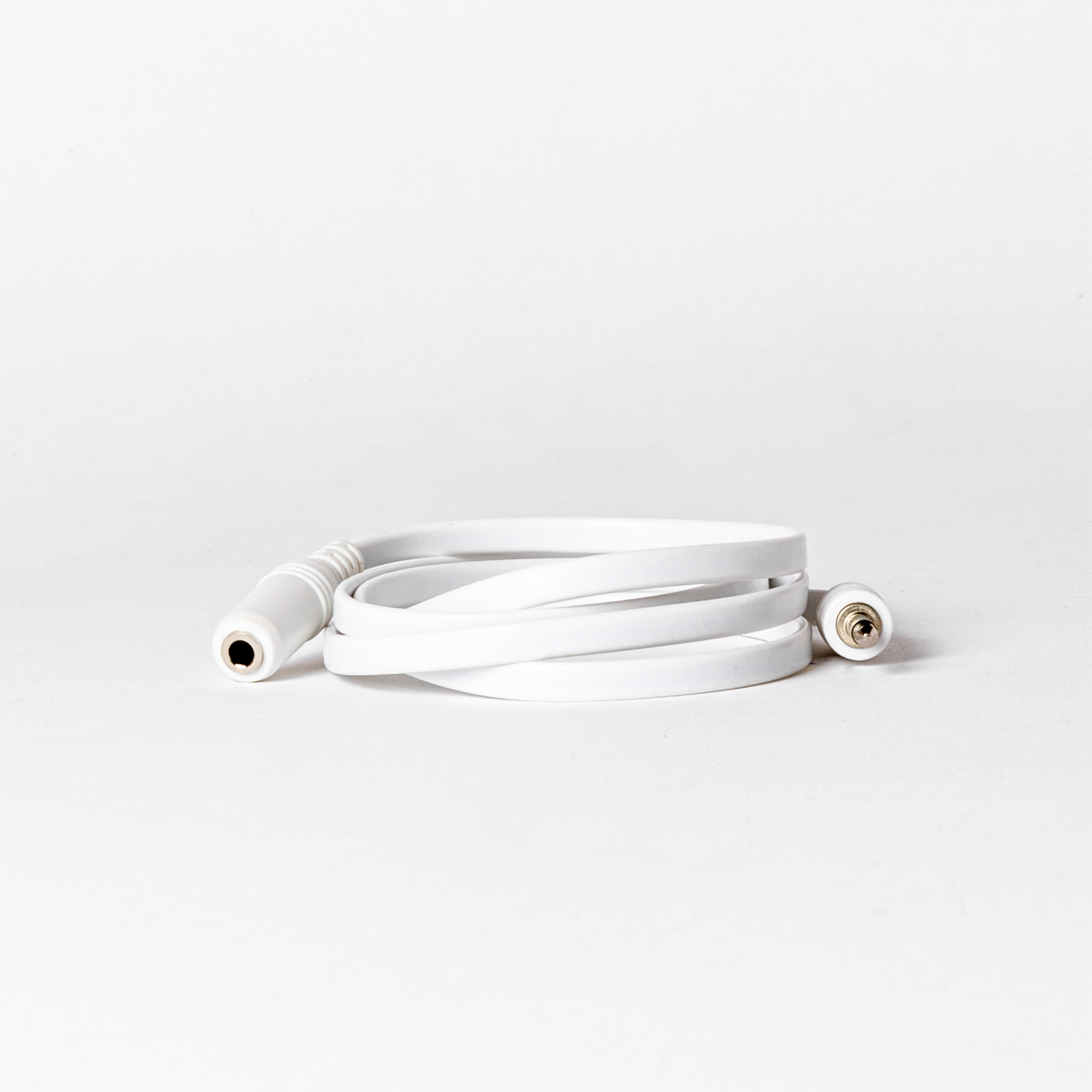 Ein aufgerolltes weißes Audiokabel mit Buchse und Stecker vor weißem Hintergrund.