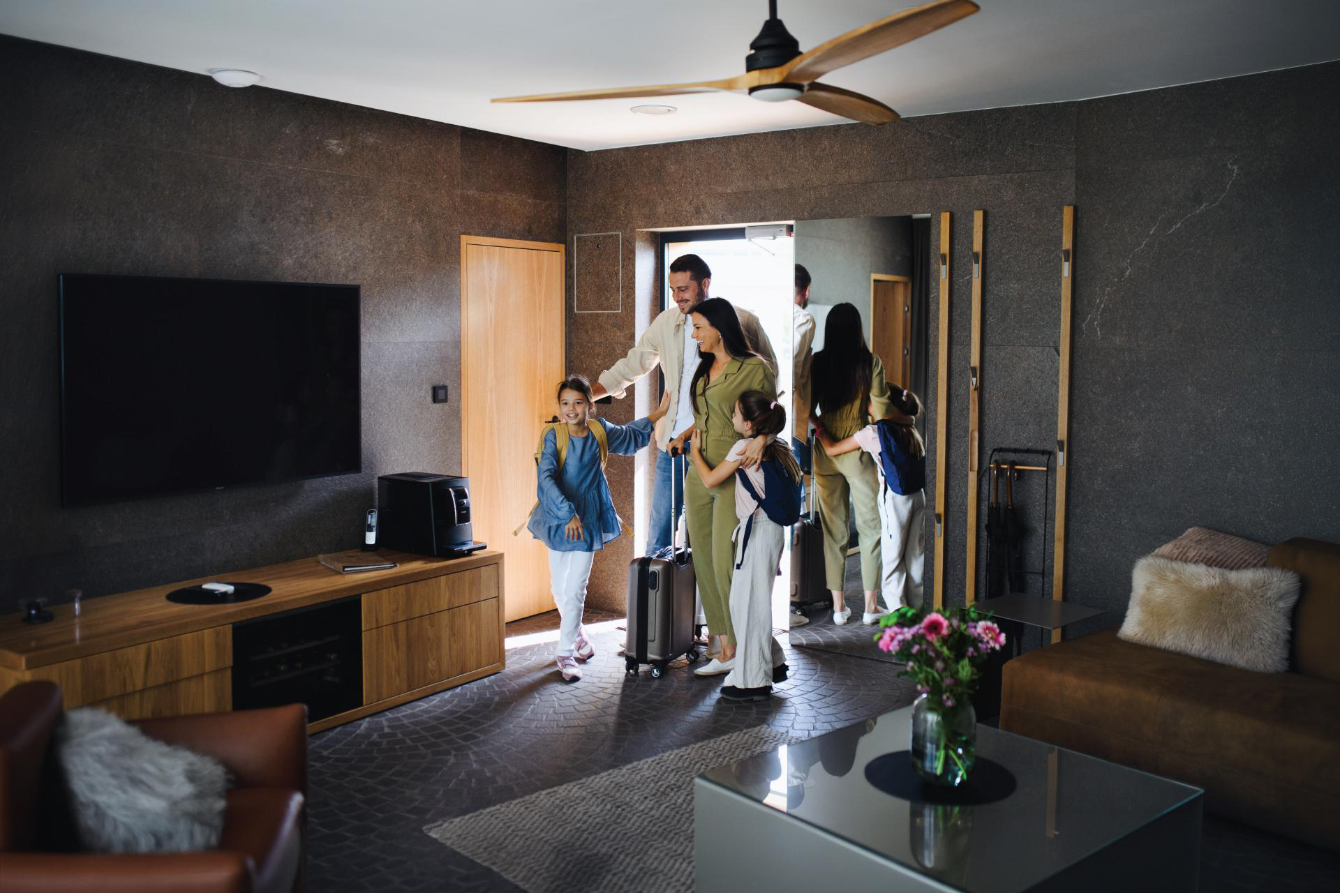 Familie mit zwei Kindern und Koffern betritt ein modernes Hotelzimmer.