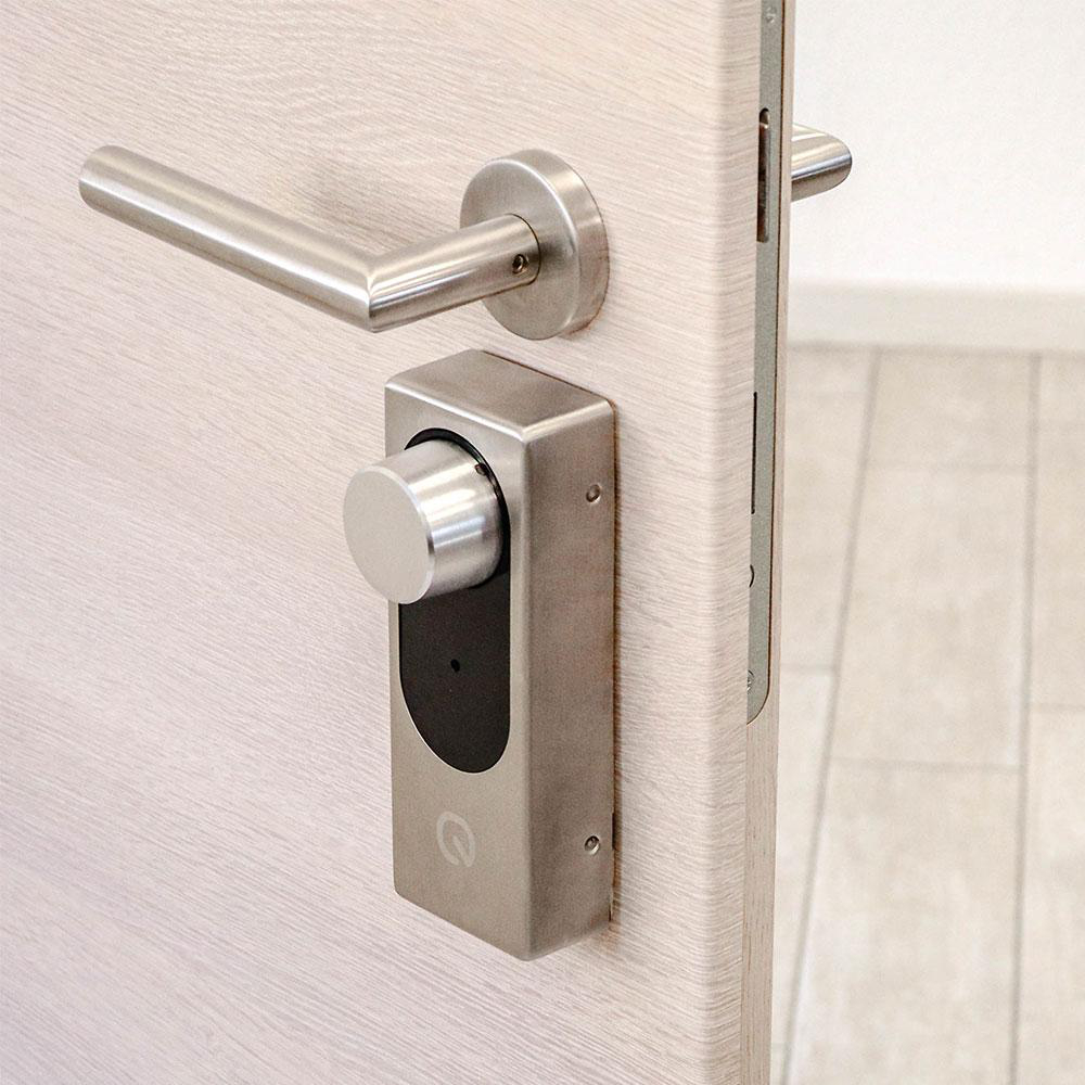 Eine helle Holztür mit Edelstahlgriff und einer modernen elektronischen Schliesseinheit.