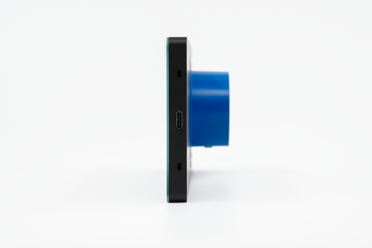 Seitenansicht eines schwarzen elektronischen Geräts mit einem USB-C-Anschluss und einem runden blauen Aufsatz.