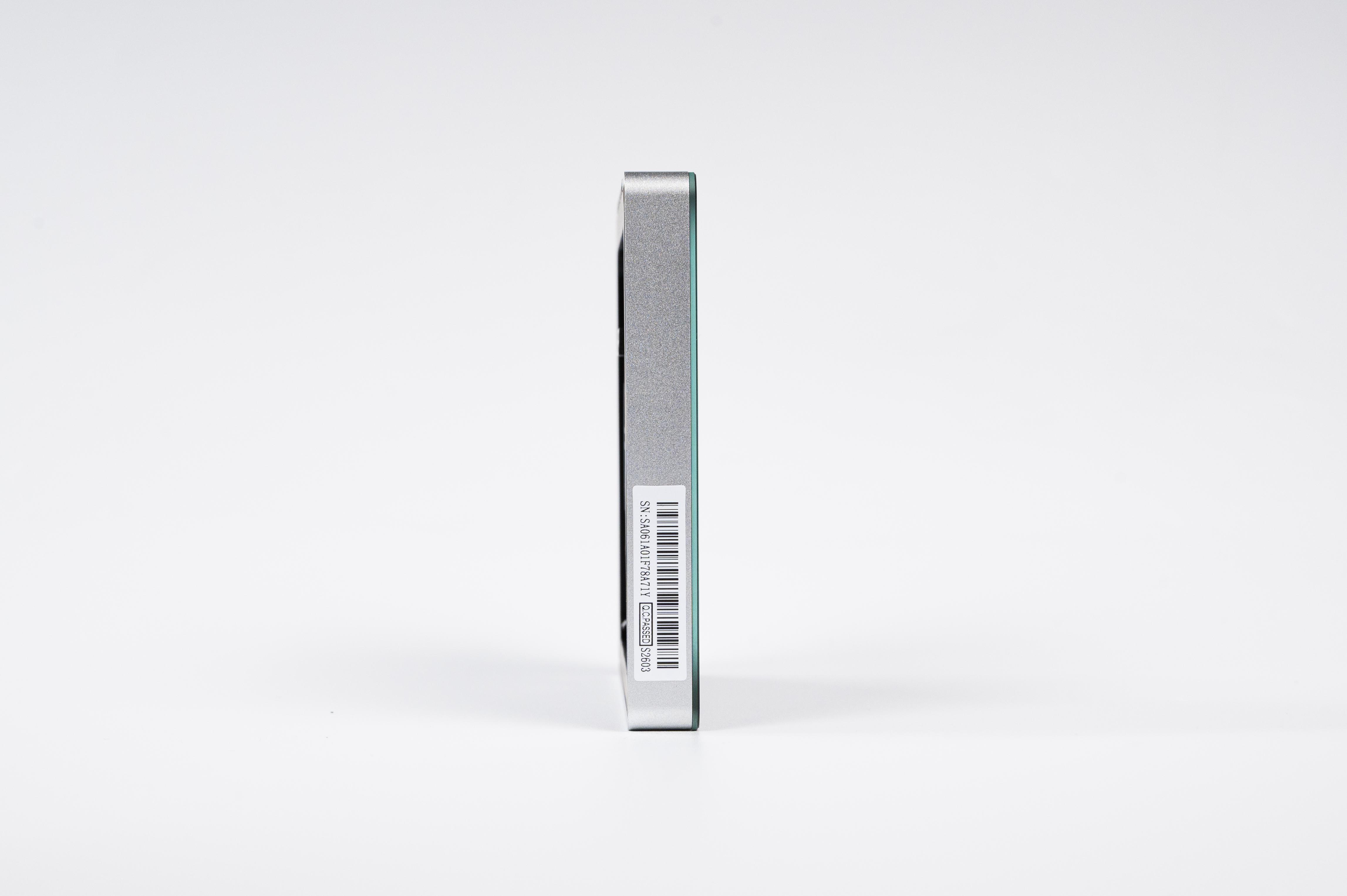Eine seitliche Ansicht eines silbernen elektronischen Geräts mit einem Barcode-Aufkleber auf einem weißen Hintergrund.
