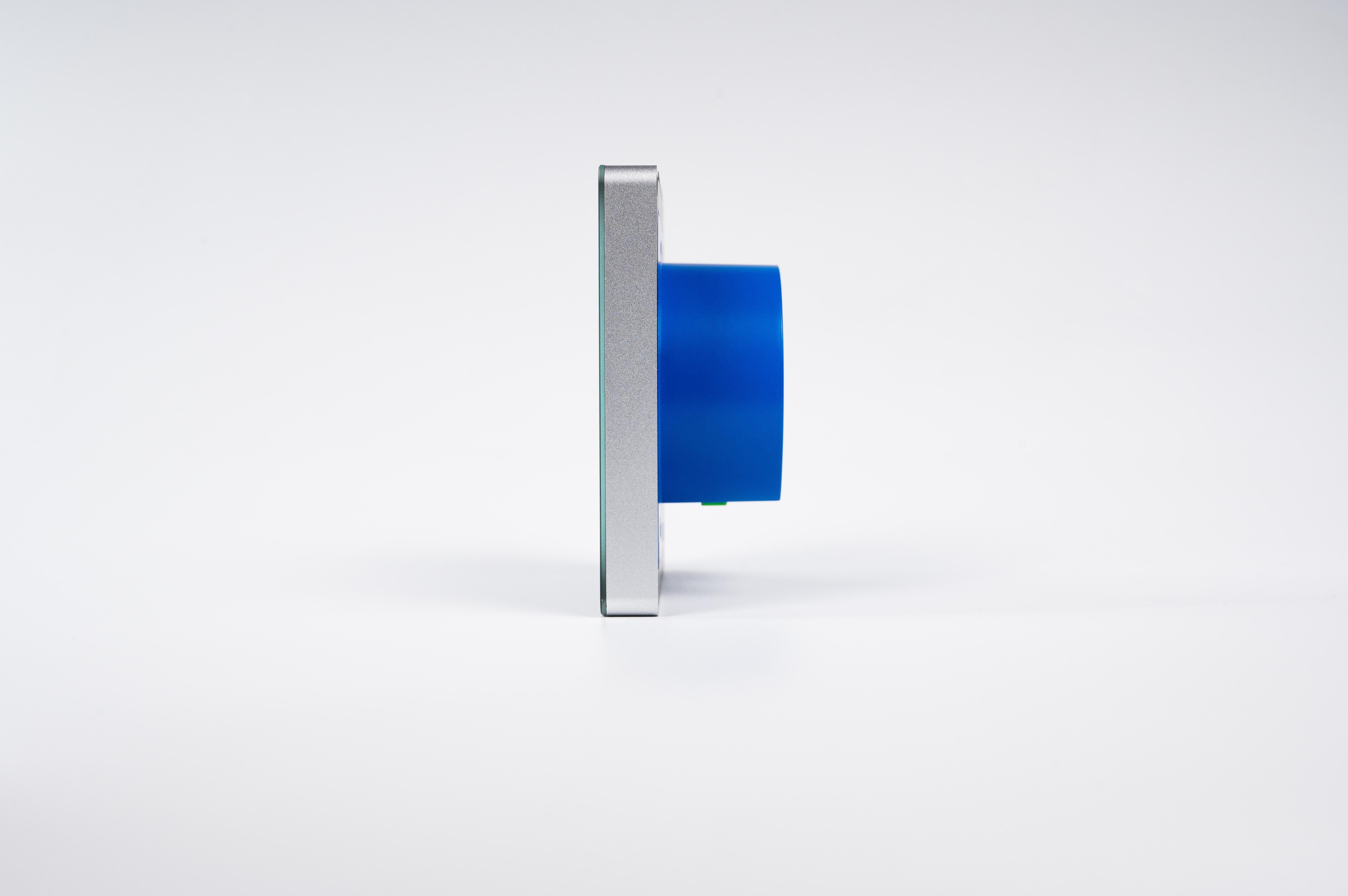 Seitenansicht eines rechteckigen silbernen Geräts mit einem runden blauen Zylinder auf weißem Hintergrund.