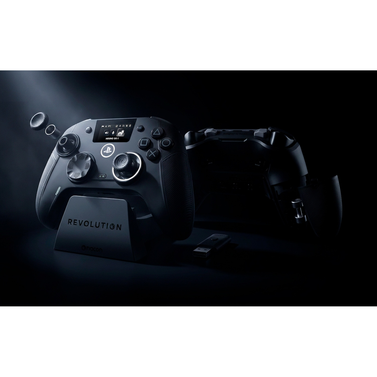 A black Revolution controller on a charging stand with detachable parts and a USB dongle against a dark background.