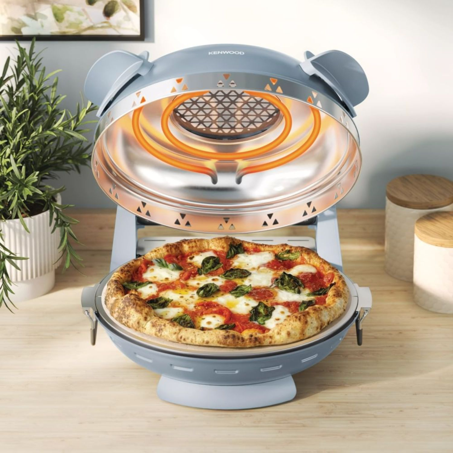 Una pizza fresca con mozzarella derretida y albahaca dentro de un horno de pizza eléctrico azul.