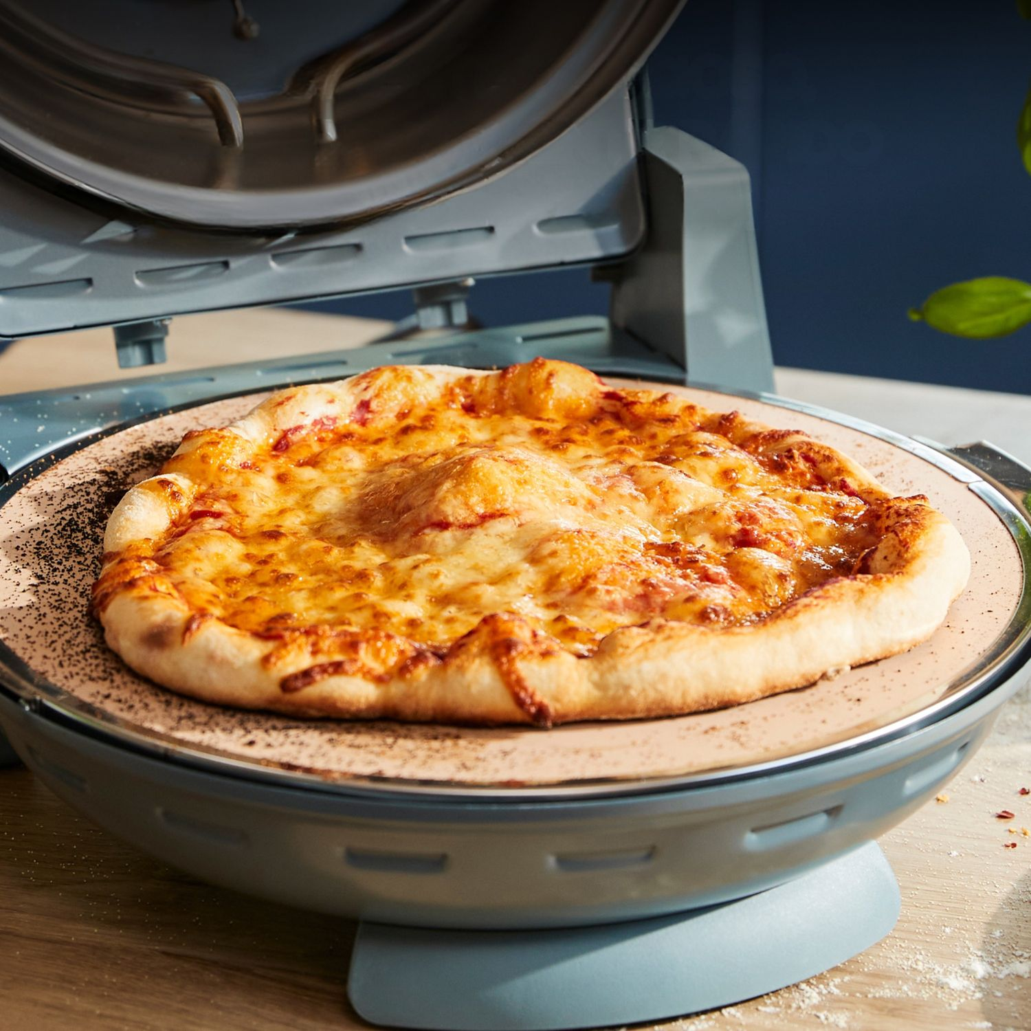 Pizza recién horneada con queso derretido en una piedra para pizza dentro de un horno eléctrico abierto.