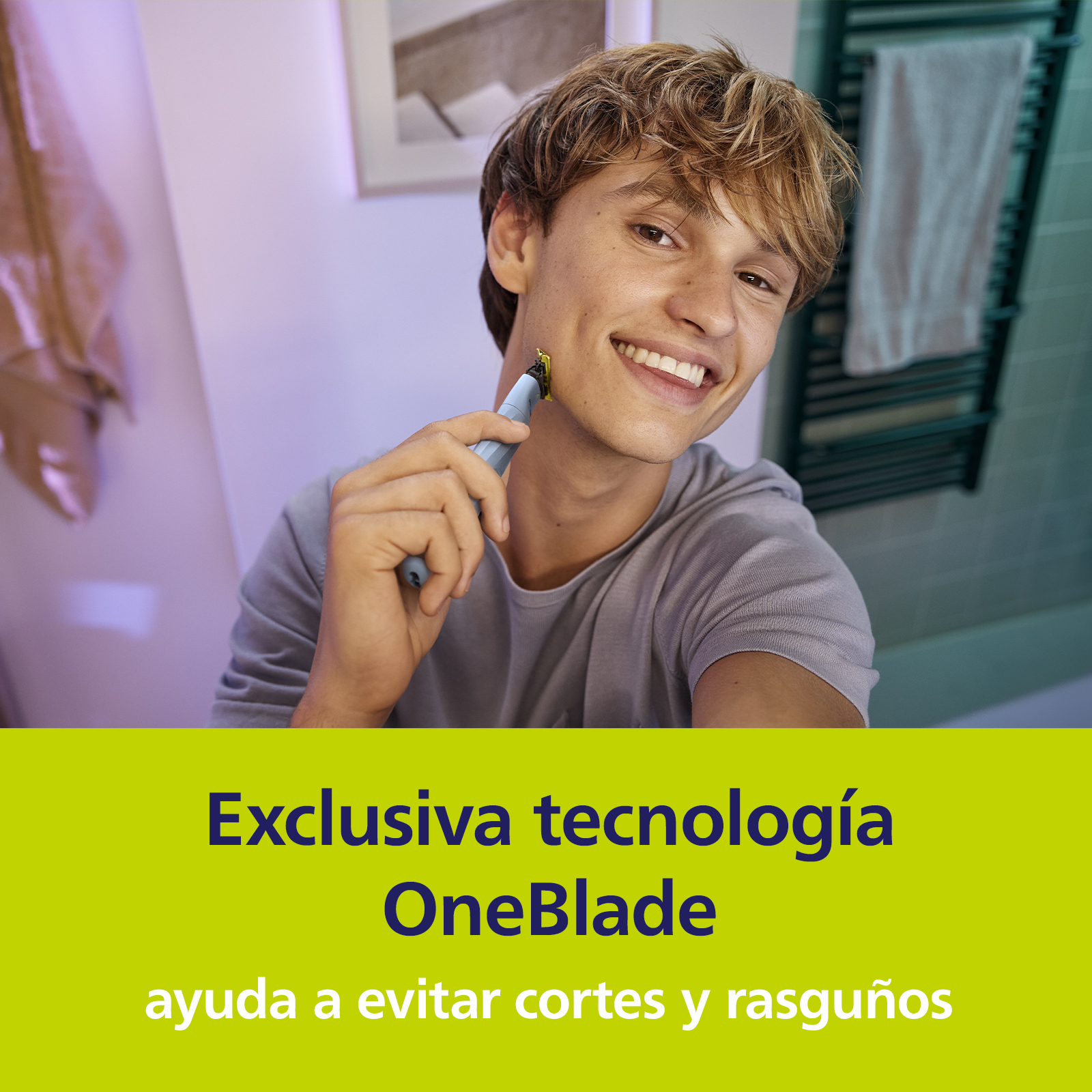 Un joven se afeita la cara en el baño usando una afeitadora OneBlade celeste.