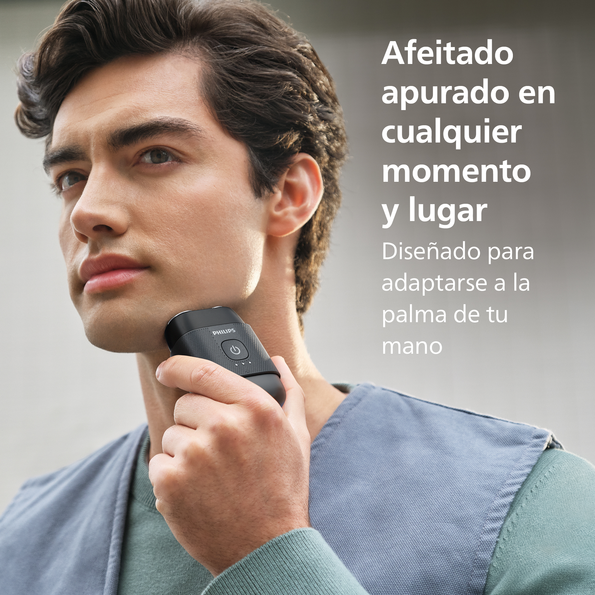 Un hombre se afeita con una pequeña afeitadora Philips negra, con texto en español al lado.