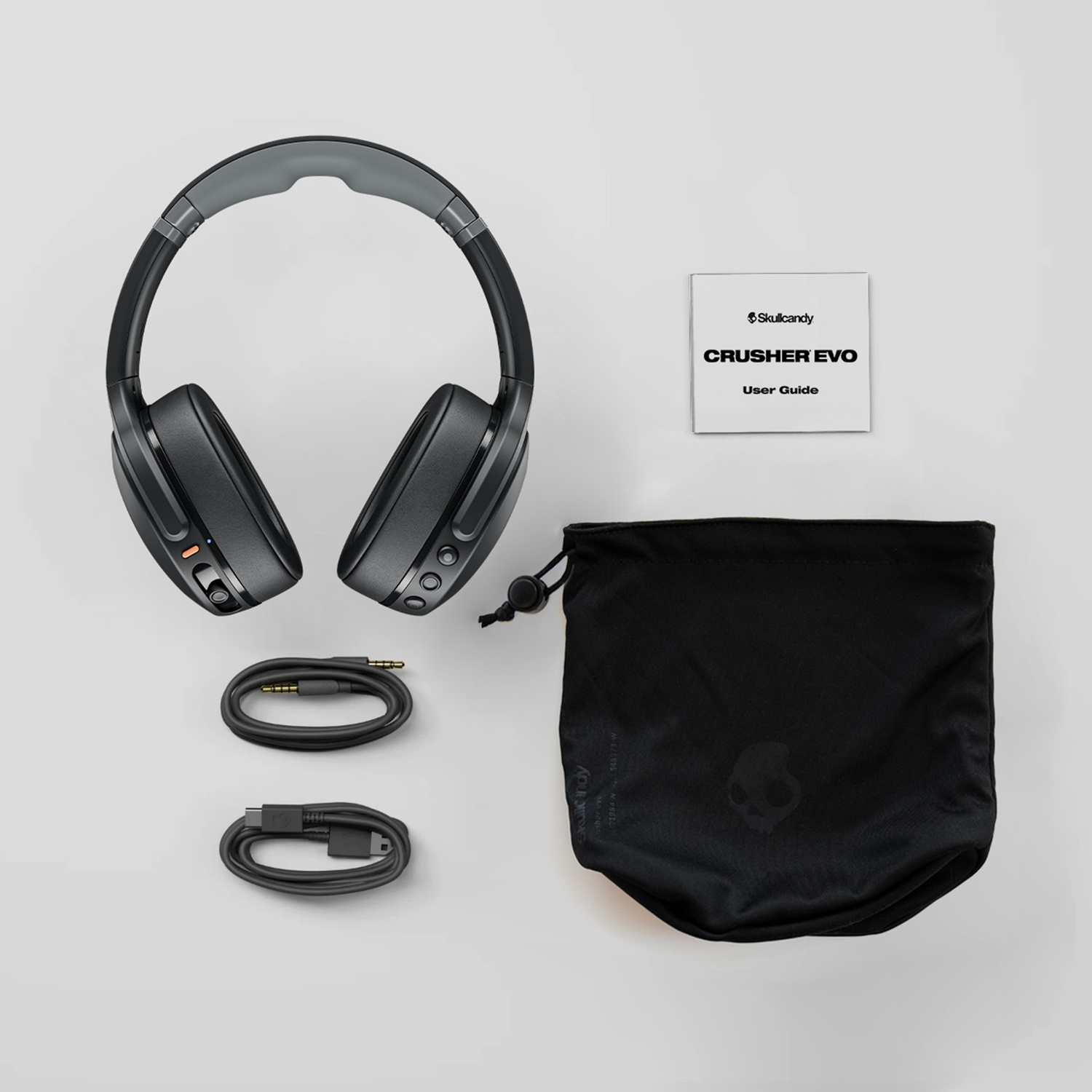 Zwarte Skullcandy Crusher Evo koptelefoon met kabels, handleiding en opberghoes.