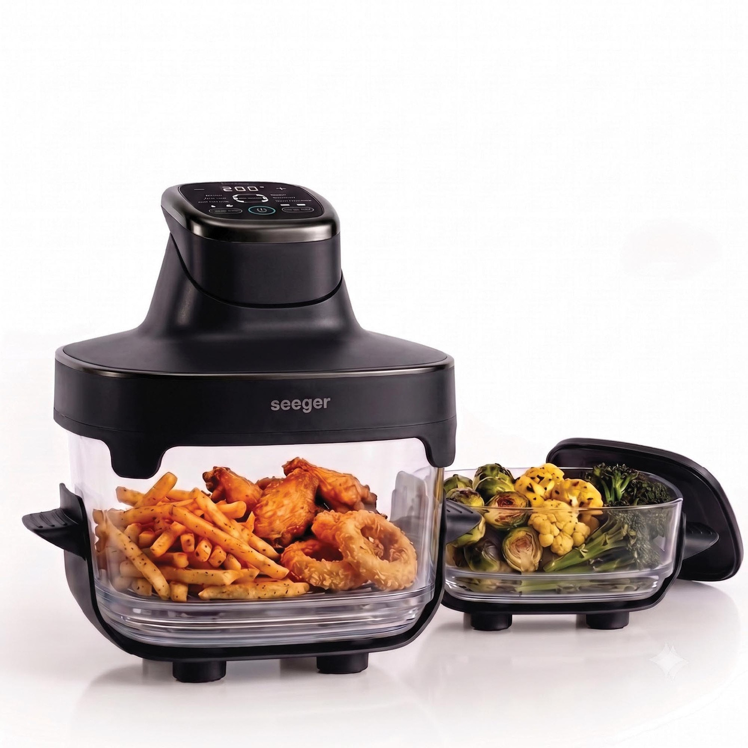 Een zwarte airfryer met glazen kom gevuld met friet, kip en uienringen.