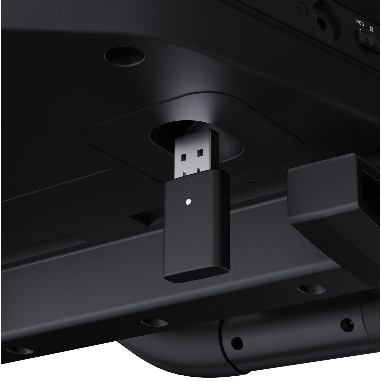 Een zwarte USB-dongle is aangesloten op de onderkant van een zwart elektronisch apparaat.
