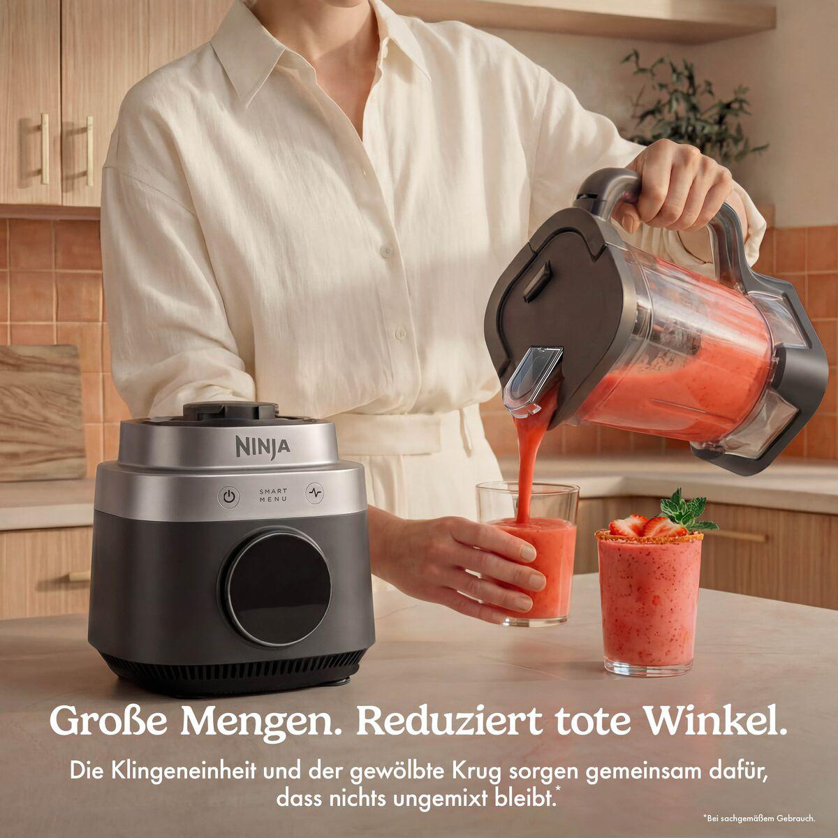 Person gießt einen roten Smoothie aus einem Ninja-Mixer in ein Glas, auf einer Küchentheke.